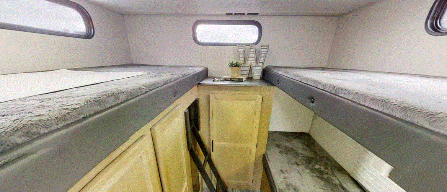 Cozy RV rental interior featuring two bunk beds with fuzzy blankets, storage cabinets, and small windows for a comfortable stay.. Forest River Cherokee Grey Wolf 2022