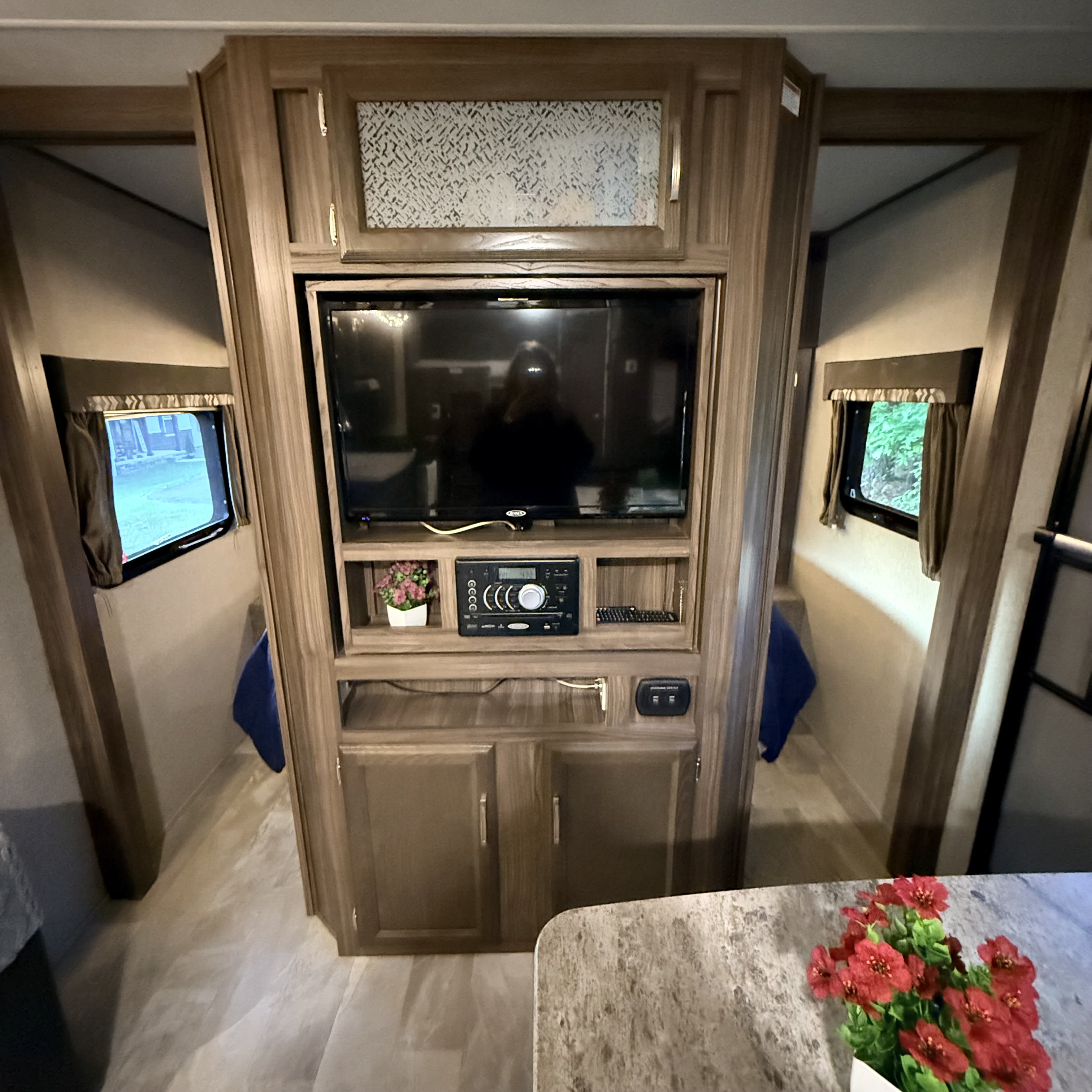 This RV rental's interior features a central entertainment center with TV & stereo, flanked by cozy bunk areas with windows.. Coachmen Apex 2018