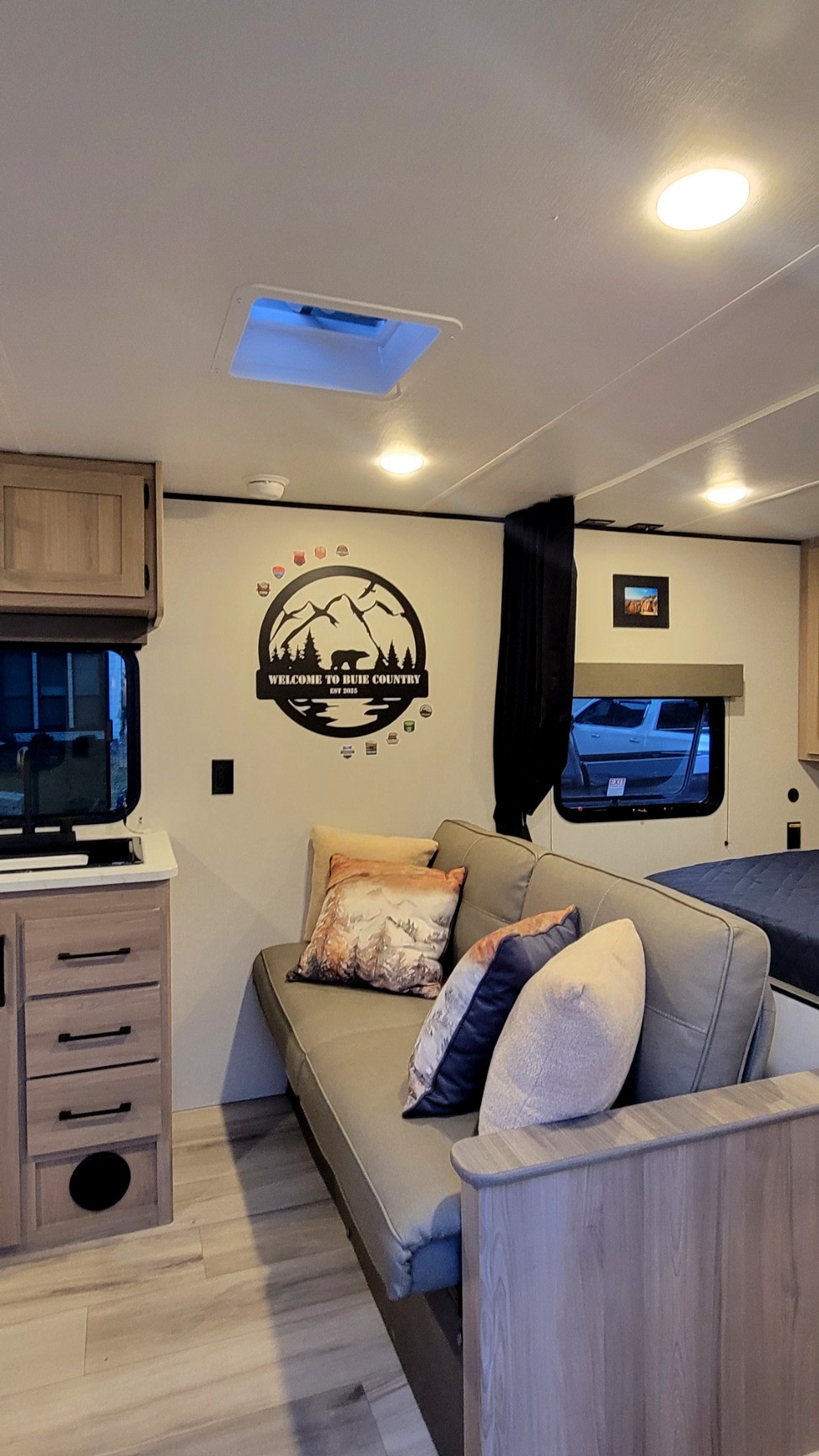 Cozy RV rental living area with a comfortable sofa, TV, and unique mountain-themed decor, perfect for travel.. Dutchmen Coleman 2025