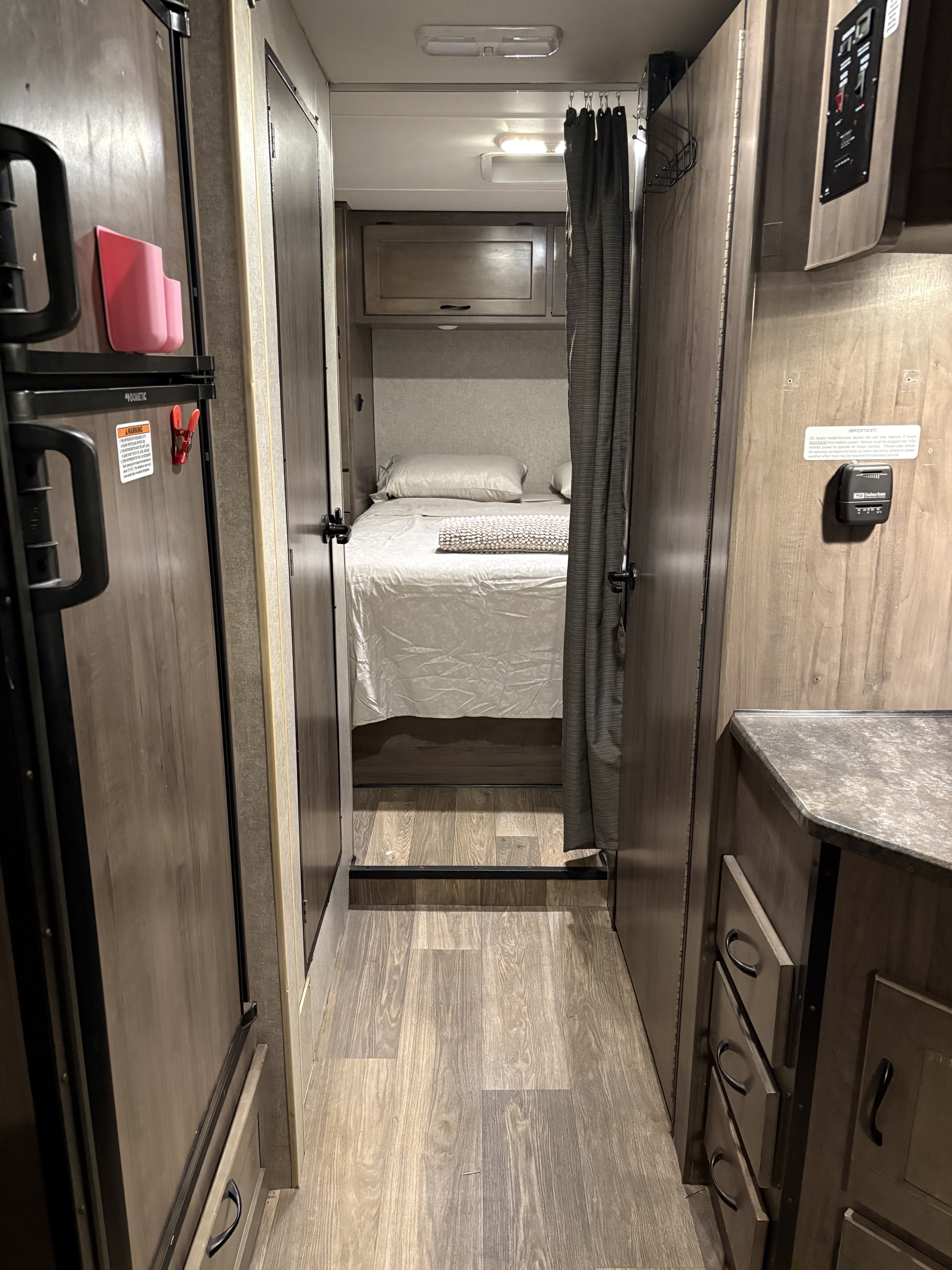 Peek inside an RV rental: compact bedroom, fridge, and galley area visible in this cozy travel trailer interior, offering a glimpse of mobile living.. Winnebago Minnie Winnie 2020