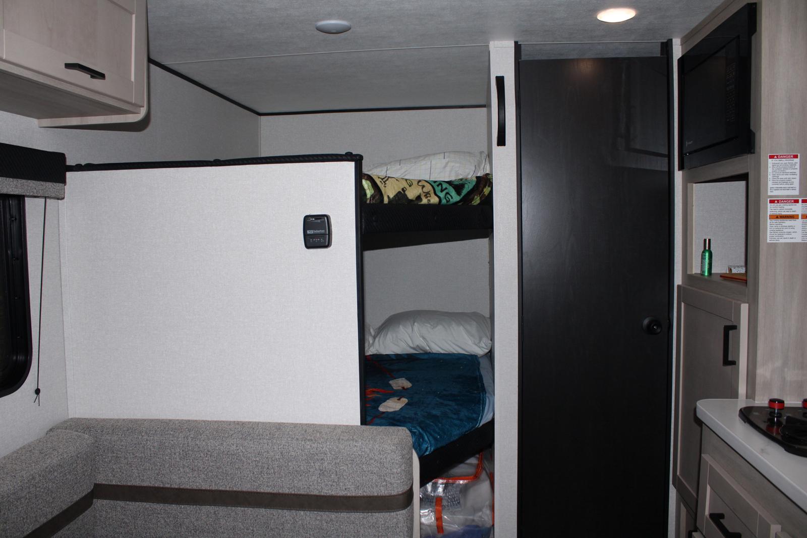 RV rental interior with cozy bunk beds, dinette seating, and compact kitchen area featuring a stovetop.. Ranger Colt 17Db 2026