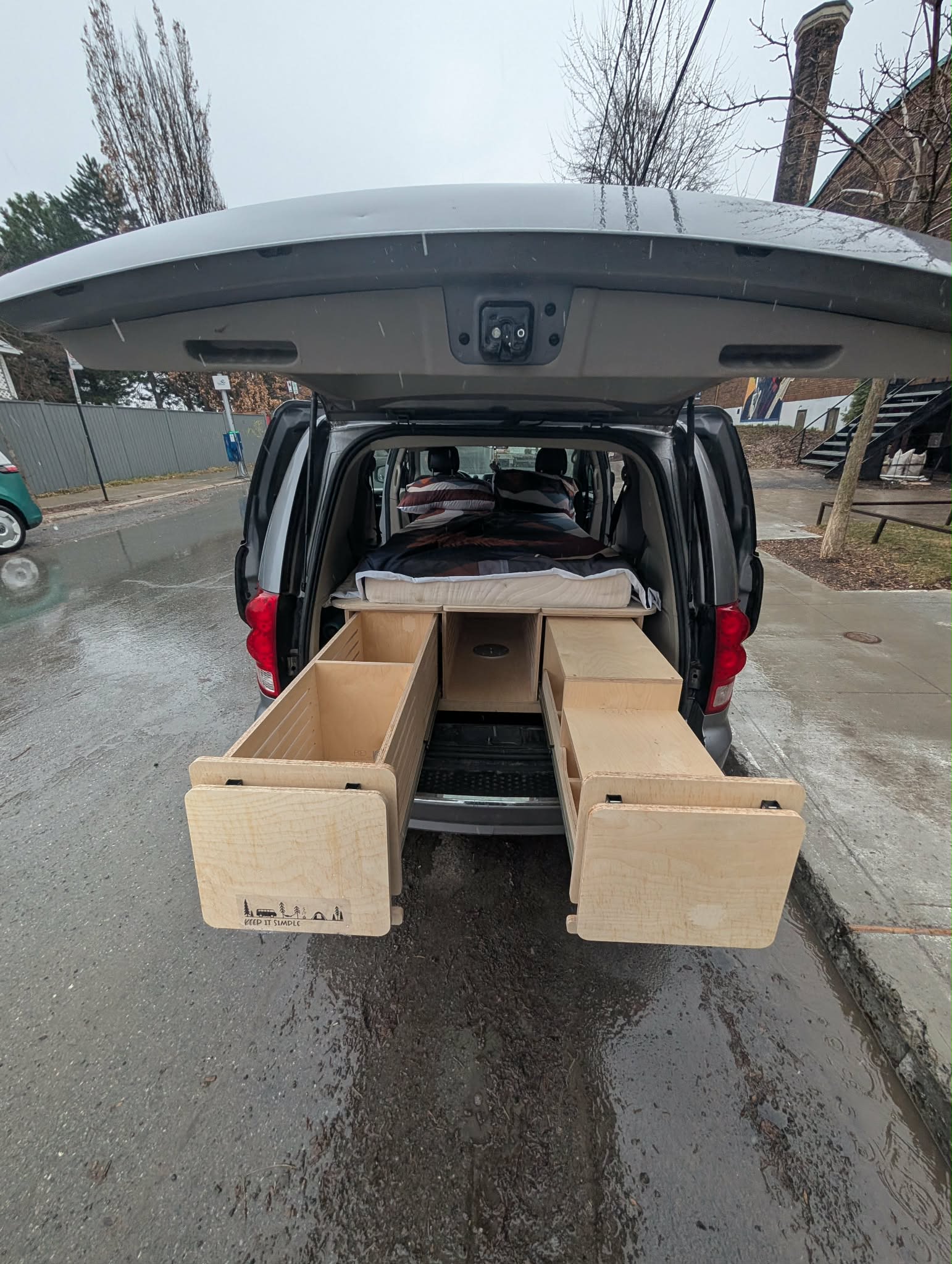 RV rental minivan conversion with custom wooden pull-out storage drawers & bed setup for compact camping.. Dodge B Van 2017