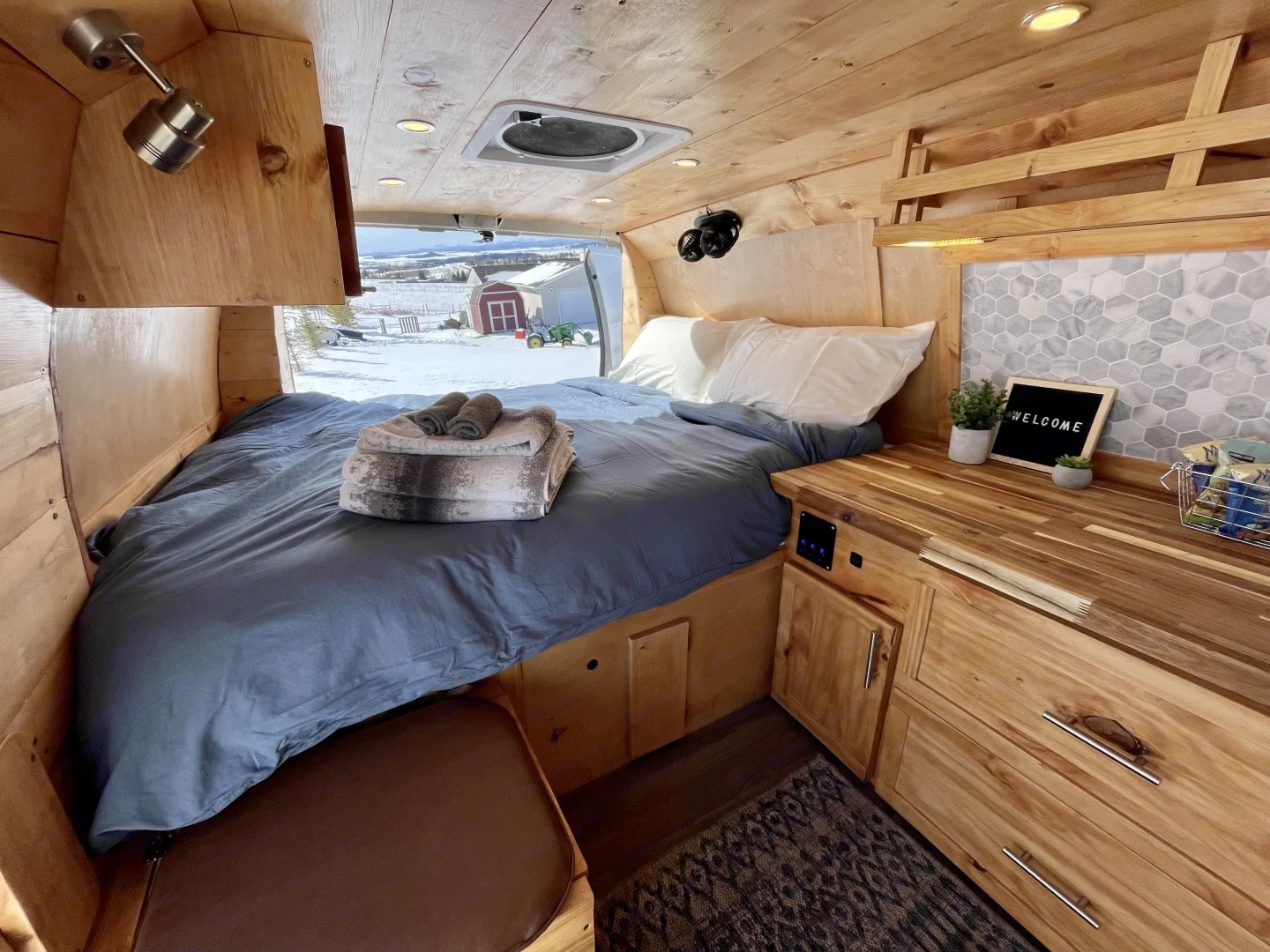 Experience this charming RV rental's wooden interior, complete with a cozy bed and a welcoming view of a snowy landscape.. Gmc Savanna 2500 2016