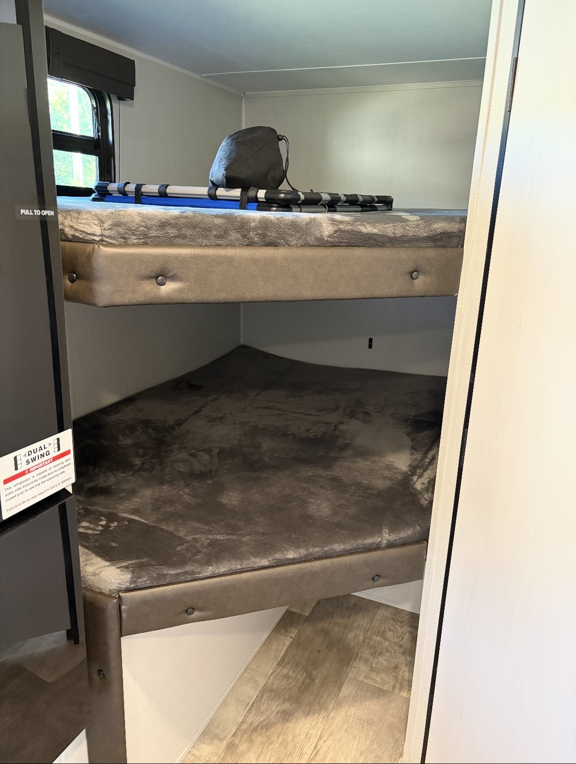 Cozy bunk beds in an RV rental, featuring soft gray blankets on both. The top bunk has a bag and rolled items, ready for travel.. Puma Palomino 2024
