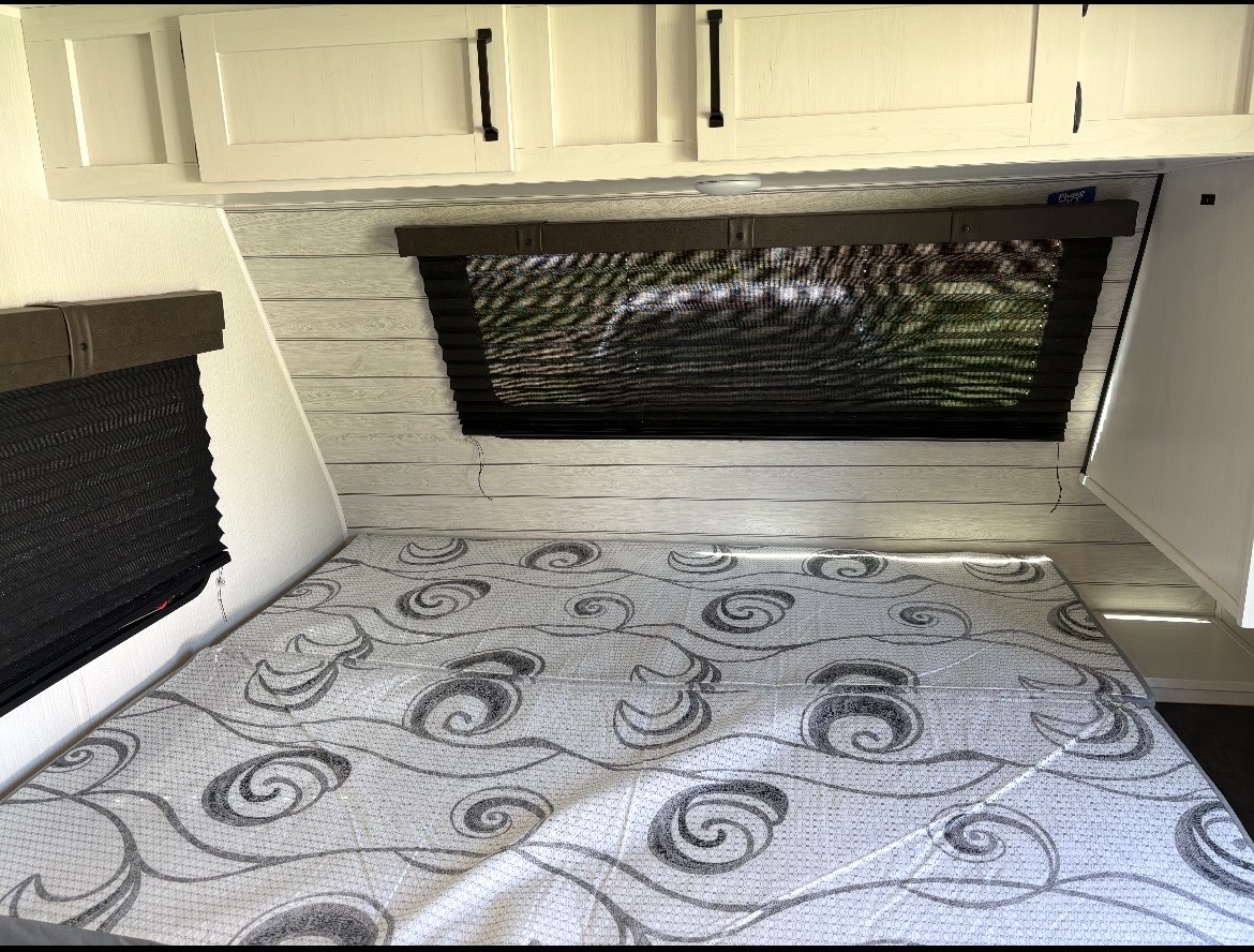 RV rental bedroom: a comfortable sleeping area with patterned mattress, wood-paneled walls, overhead cabinets, and dark blinds.. Puma Palomino 2024