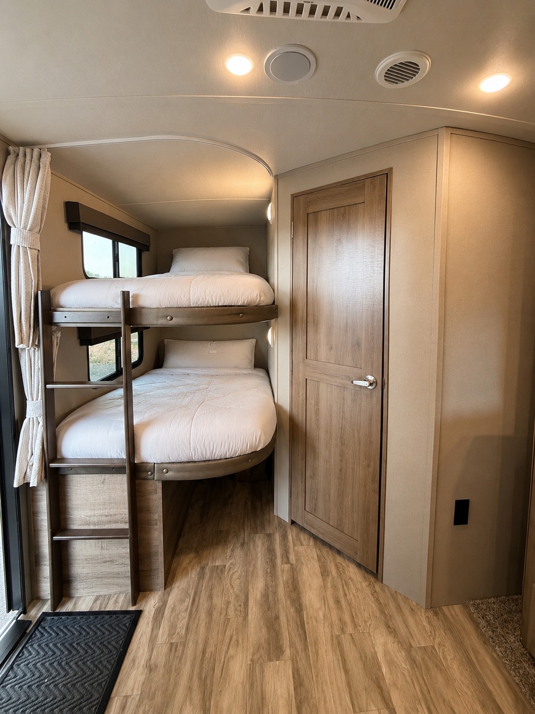 Inside a modern RV rental, featuring cozy bunk beds, a wooden door, and laminate flooring. Ideal for travel.. Grand Design Imagine 2021