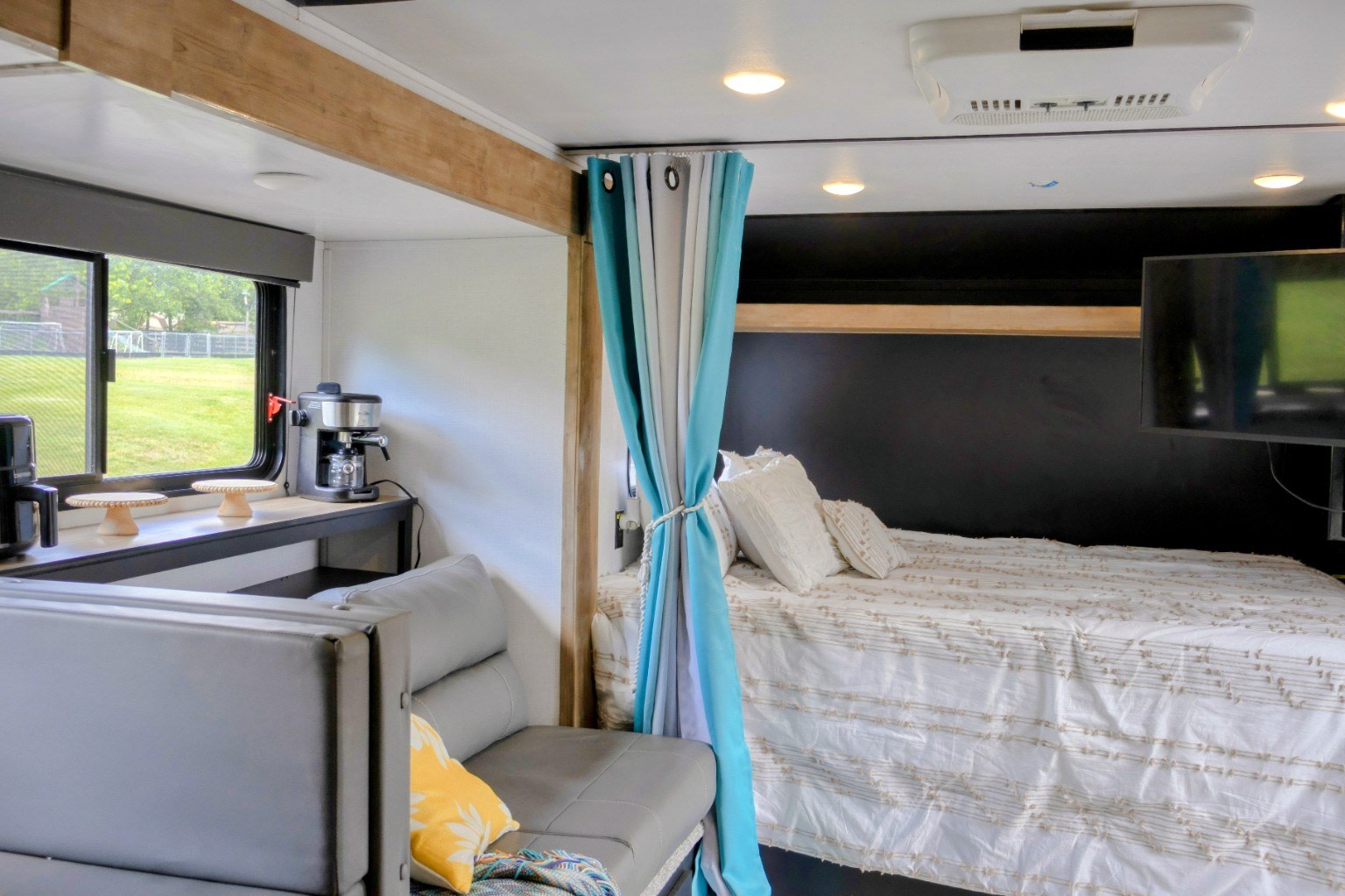 Cozy RV rental interior showing a bedroom with TV, compact kitchen area with coffee maker, and seating for travel trailer trips.. Keystone RV Springdale 2022