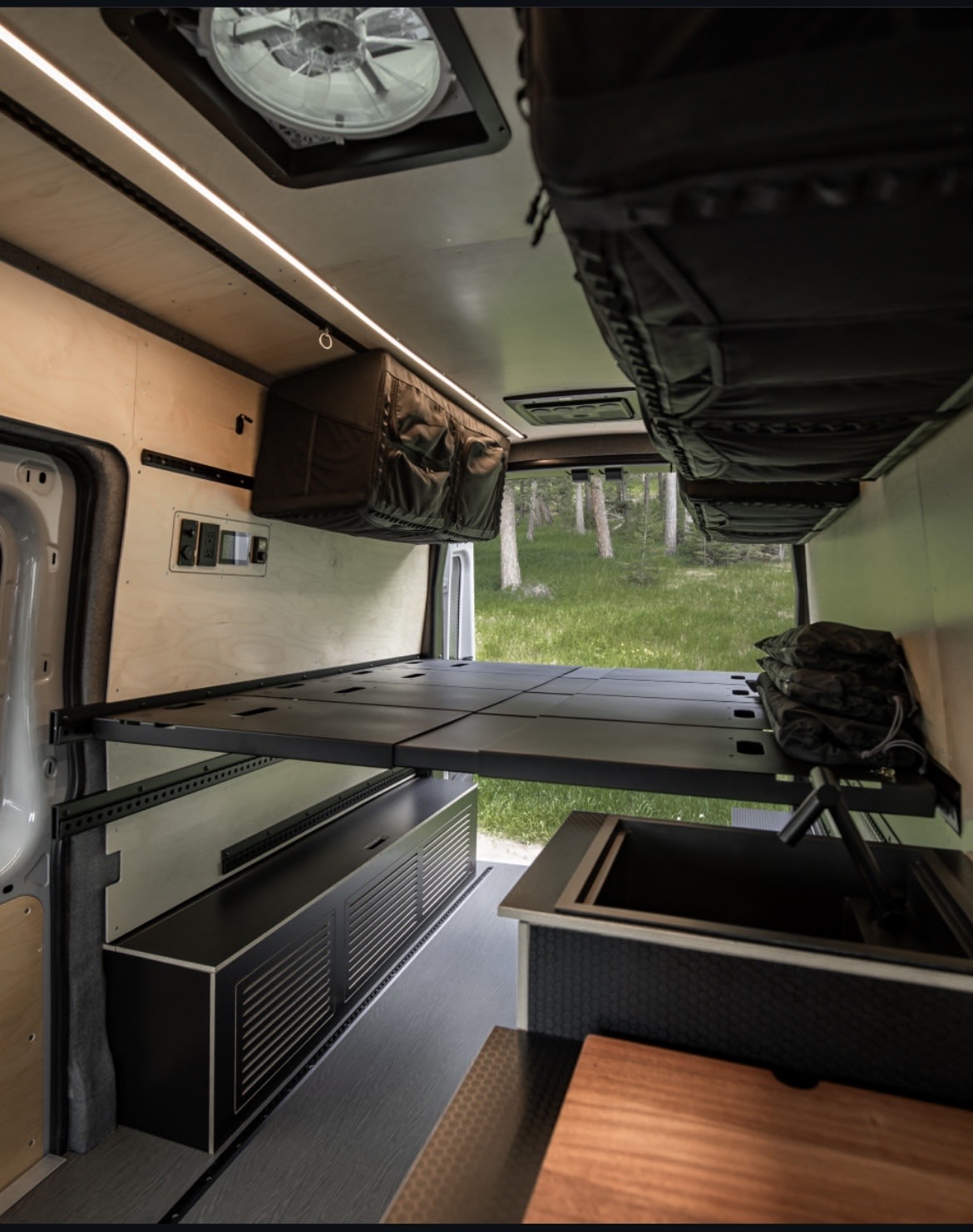 Spacious RV rental interior with a raised bed, modern kitchen sink, and ample storage for comfortable van life adventures.. Ford Transit Trail 2023