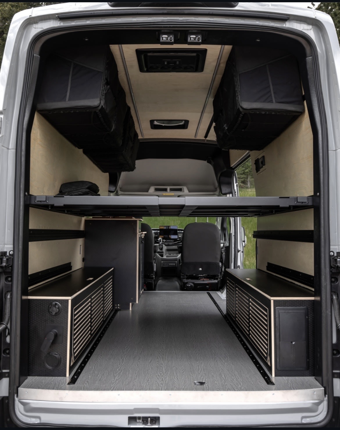 Spacious RV rental interior: customized camper van with modular bed, overhead storage, and built-in cabinets.. Ford Transit Trail 2023