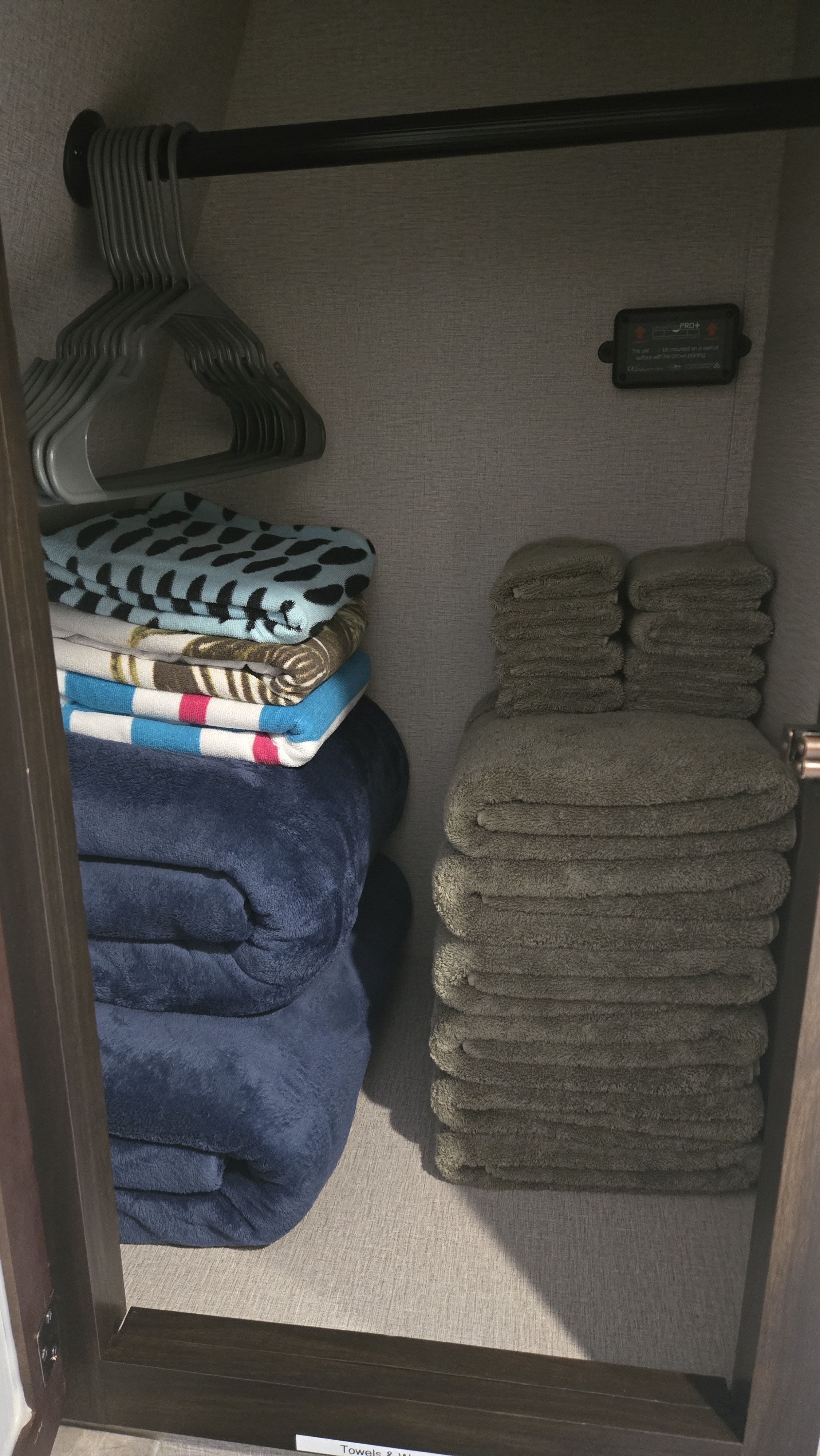 Organized RV rental closet with hangers, stacked blankets, and folded towels. Efficient storage for linens in a compact space.. Grand Design Momentum 2020