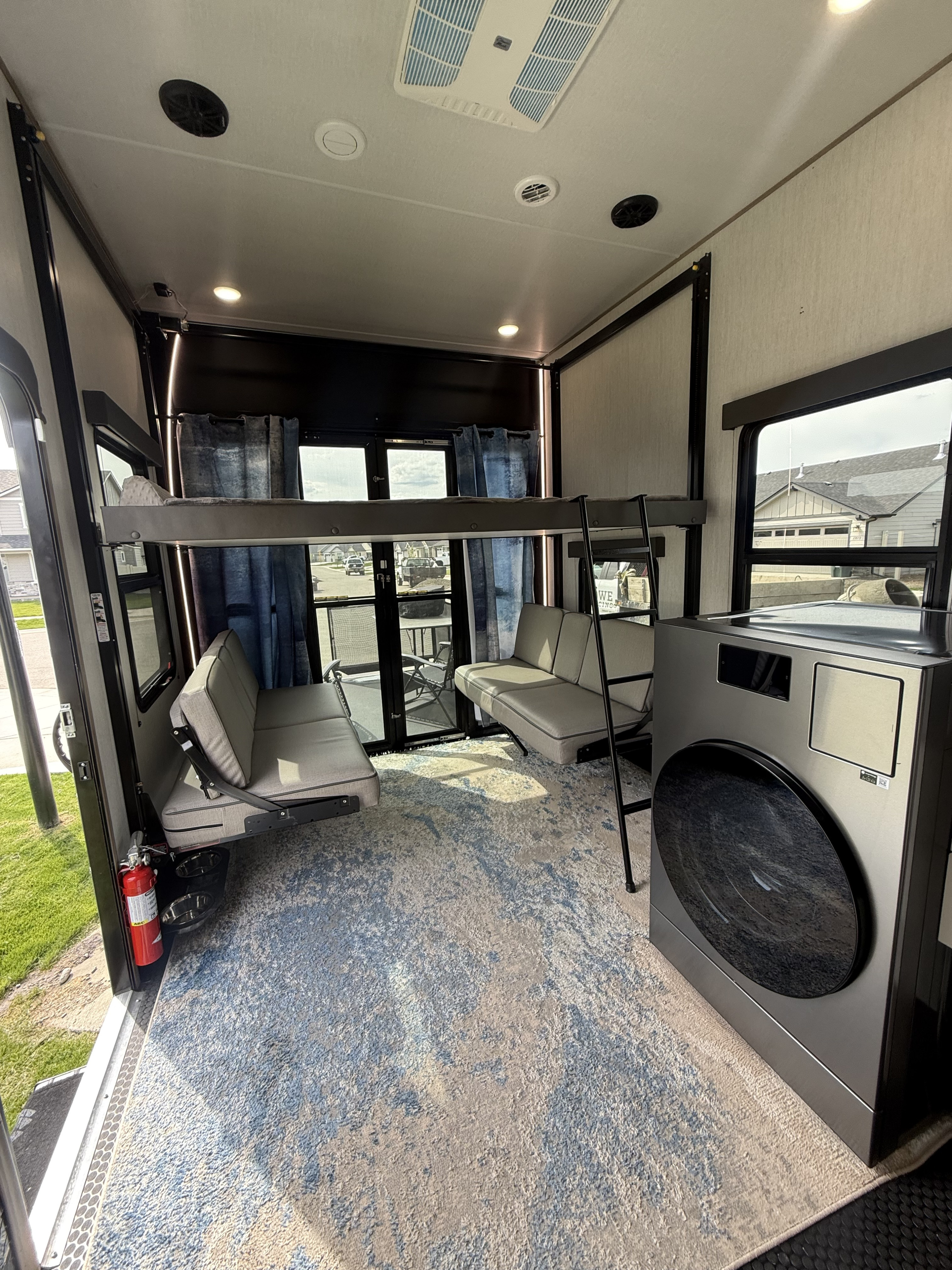 Spacious RV rental interior featuring bunk beds, convertible seating, a modern washer/dryer, and a decorative rug.. Grand Design Momentum 2024