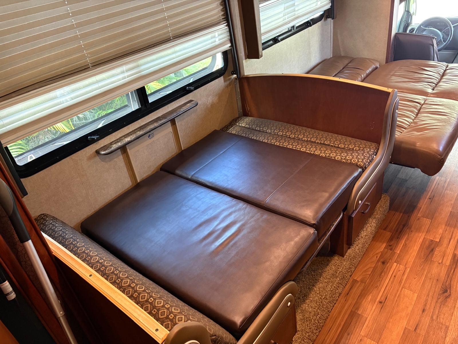 RV rental interior: A brown leather dinette converted to a bed, with another seating area visible in this cozy space.. Jayco Greyhawk 2015