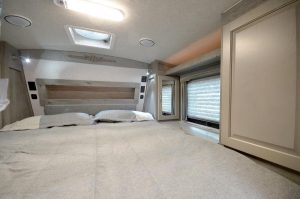 Discover this comfortable RV rental bedroom, showcasing a large bed, skylight, and window with blinds, ideal for travel.. Northwood Mfg Arctic Fox 2025