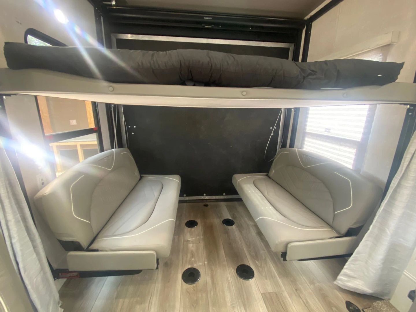 RV rental interior features an overhead bunk bed and two gray convertible sofas, creating a flexible camper living space.. Eclipse Recreational Vehicles Attitude 2022