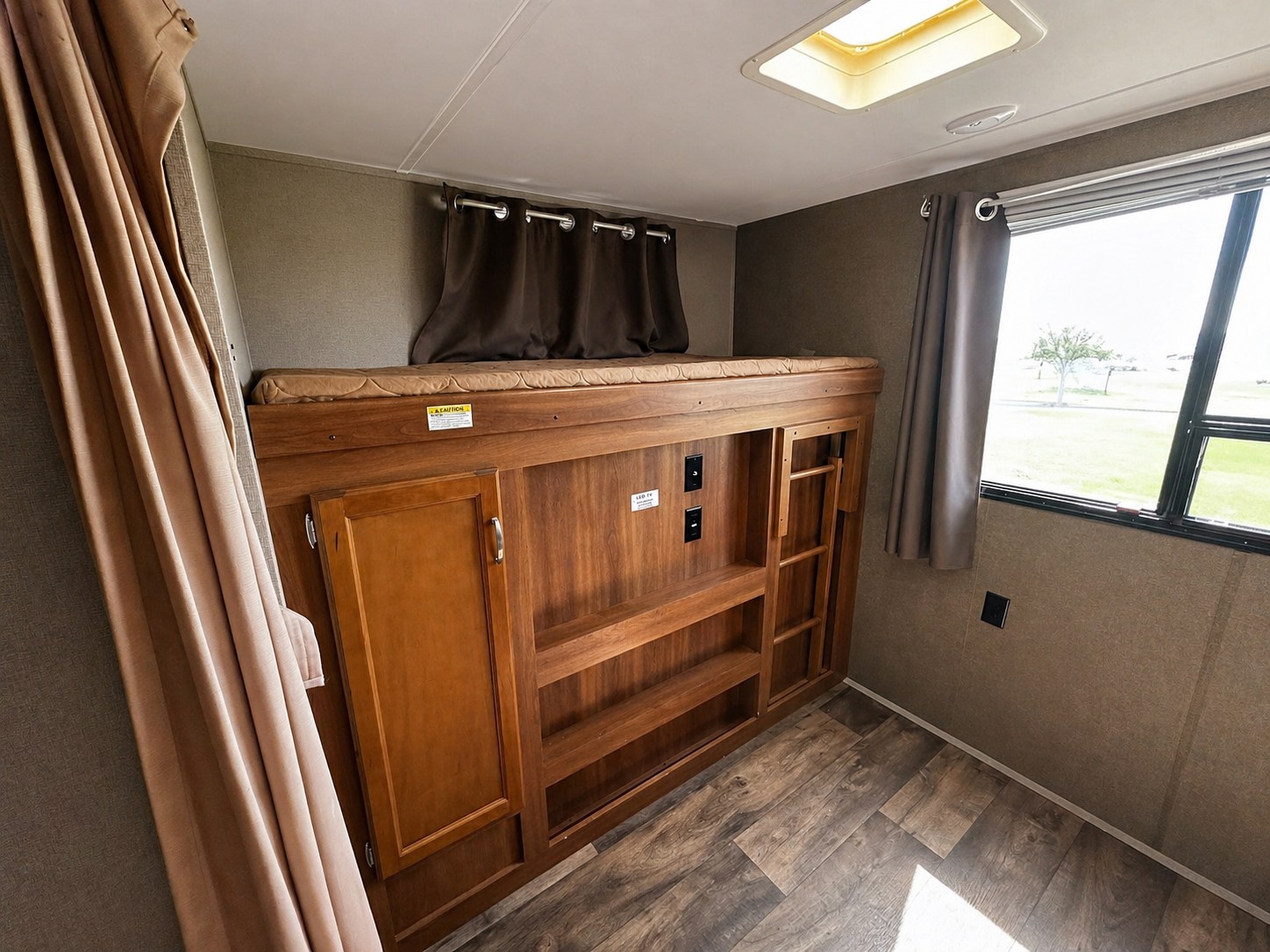 Inside an RV rental, a compact bunk bed setup with built-in storage, a ladder, and a window for scenic views.. Keystone RV Springdale 2017