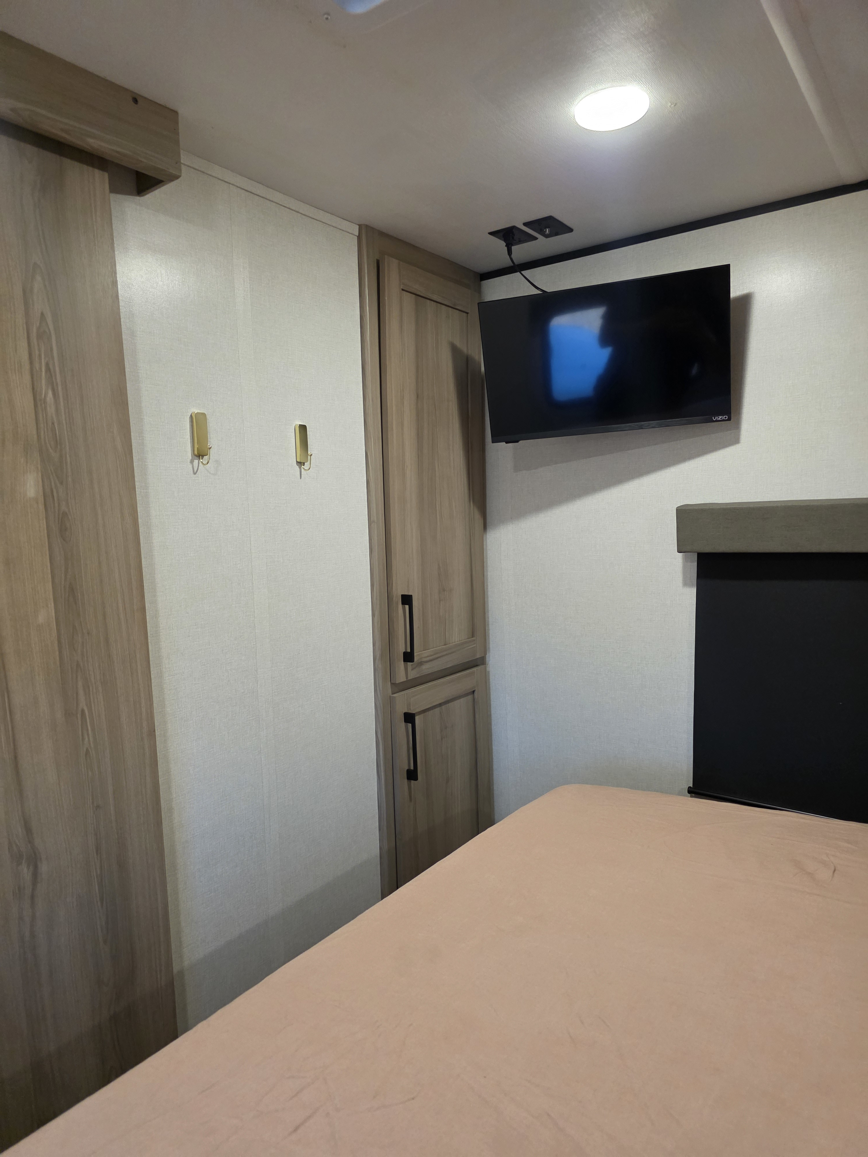 This RV rental's cozy bedroom offers a mounted TV, storage, and a comfortable bed in a compact, well-designed space.. Keystone RV Coleman Legacy 2026