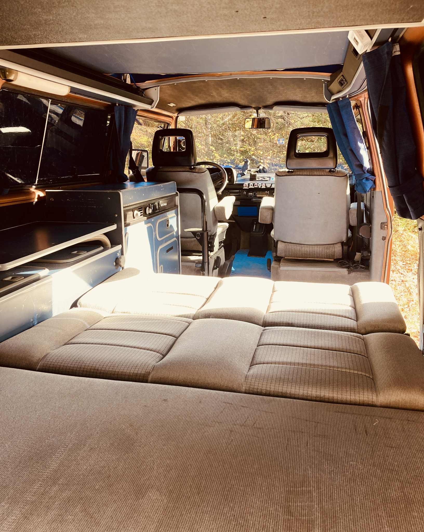 Cozy camper van interior for your next RV rental adventure, featuring a bed, kitchen, and front seats.. Volkswagen T3 Westfalia 1988