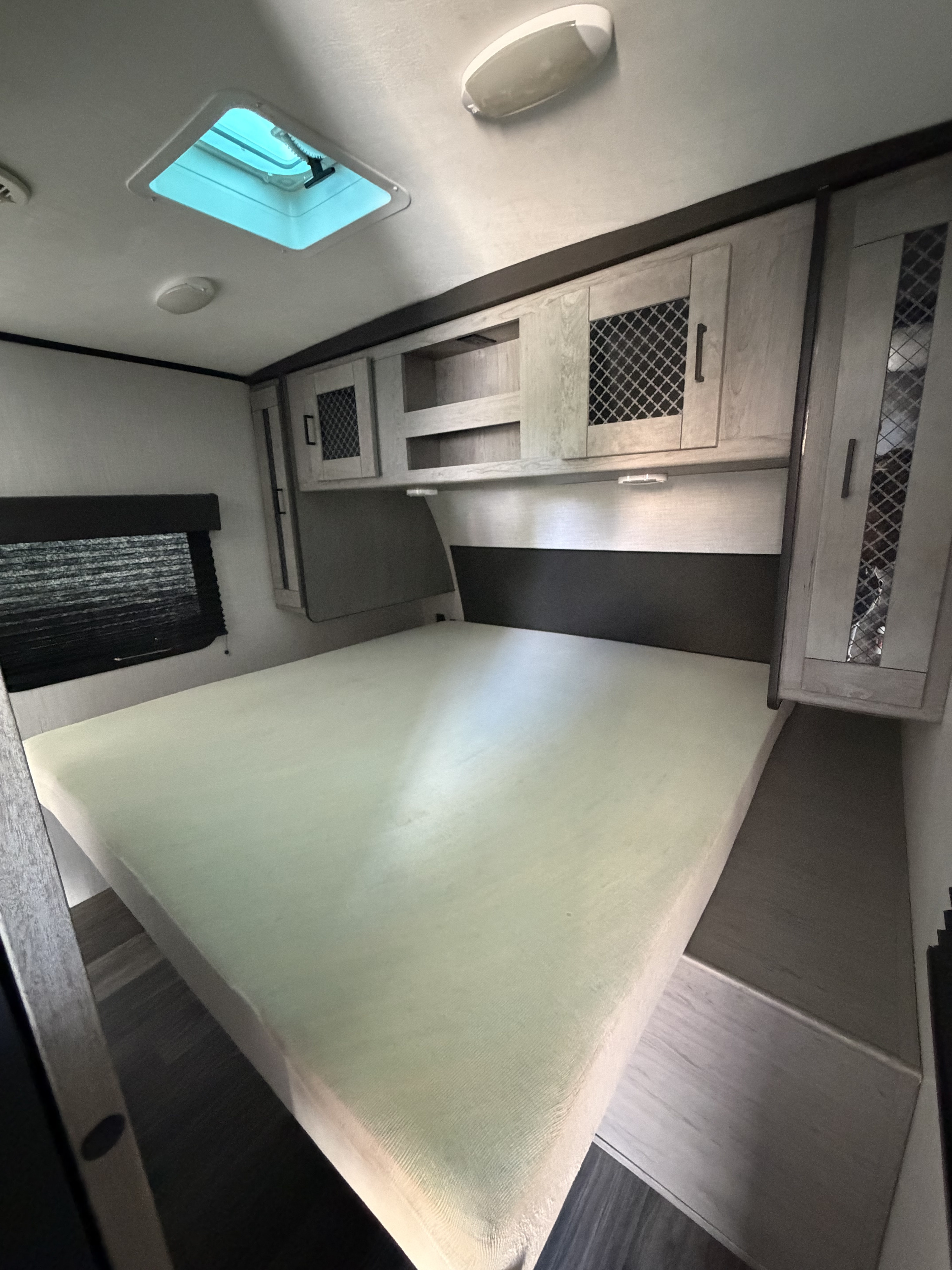 Cozy RV rental bedroom with a large bed, overhead cabinets, and a bright skylight. Modern, functional interior.. Heartland RVs Mallard 2021