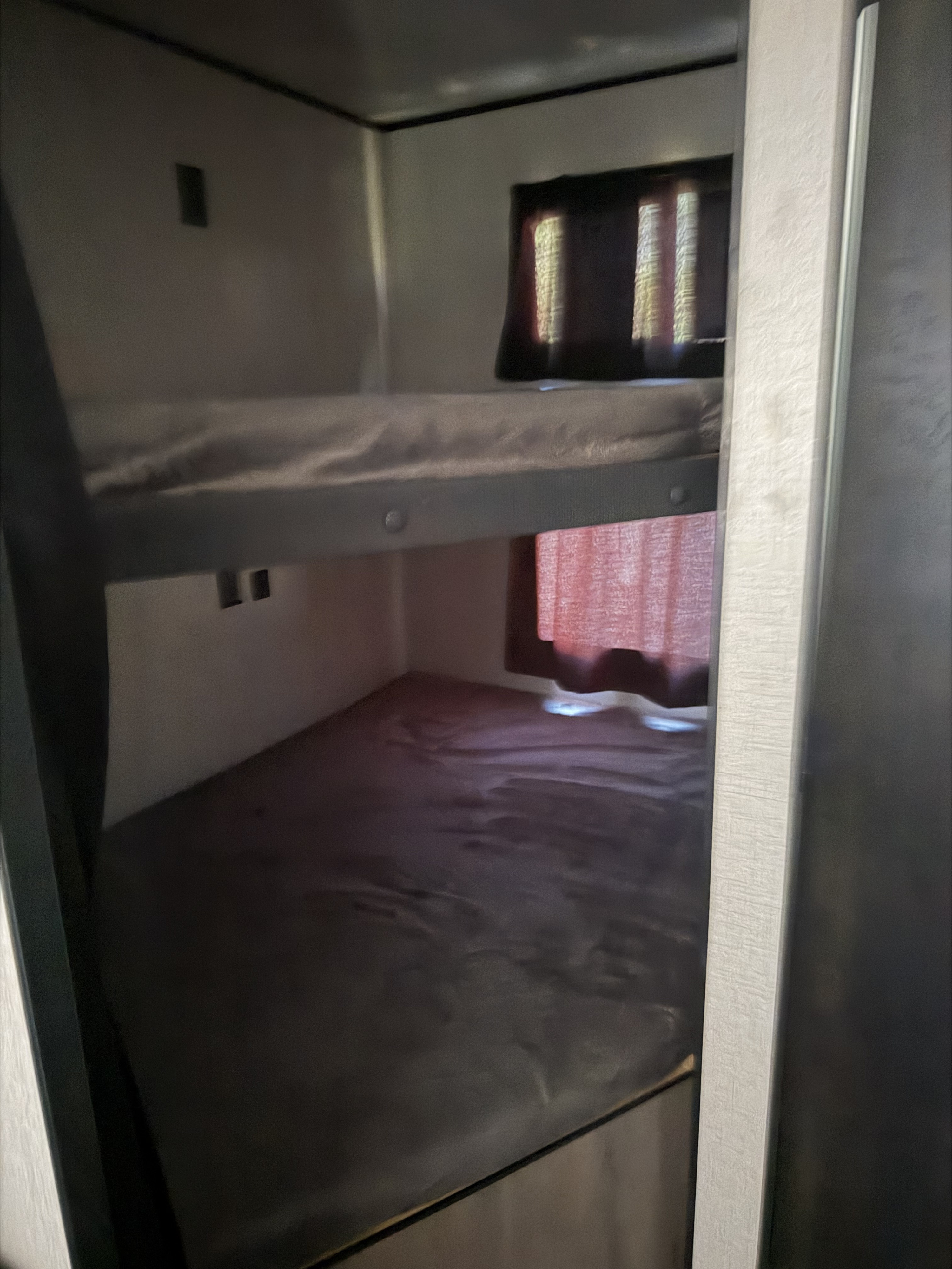 RV rental interior view: compact bunk beds with mattresses offer a cozy sleeping area, featuring a window and wall outlets.. Starcraft Autumn Ridge 2022