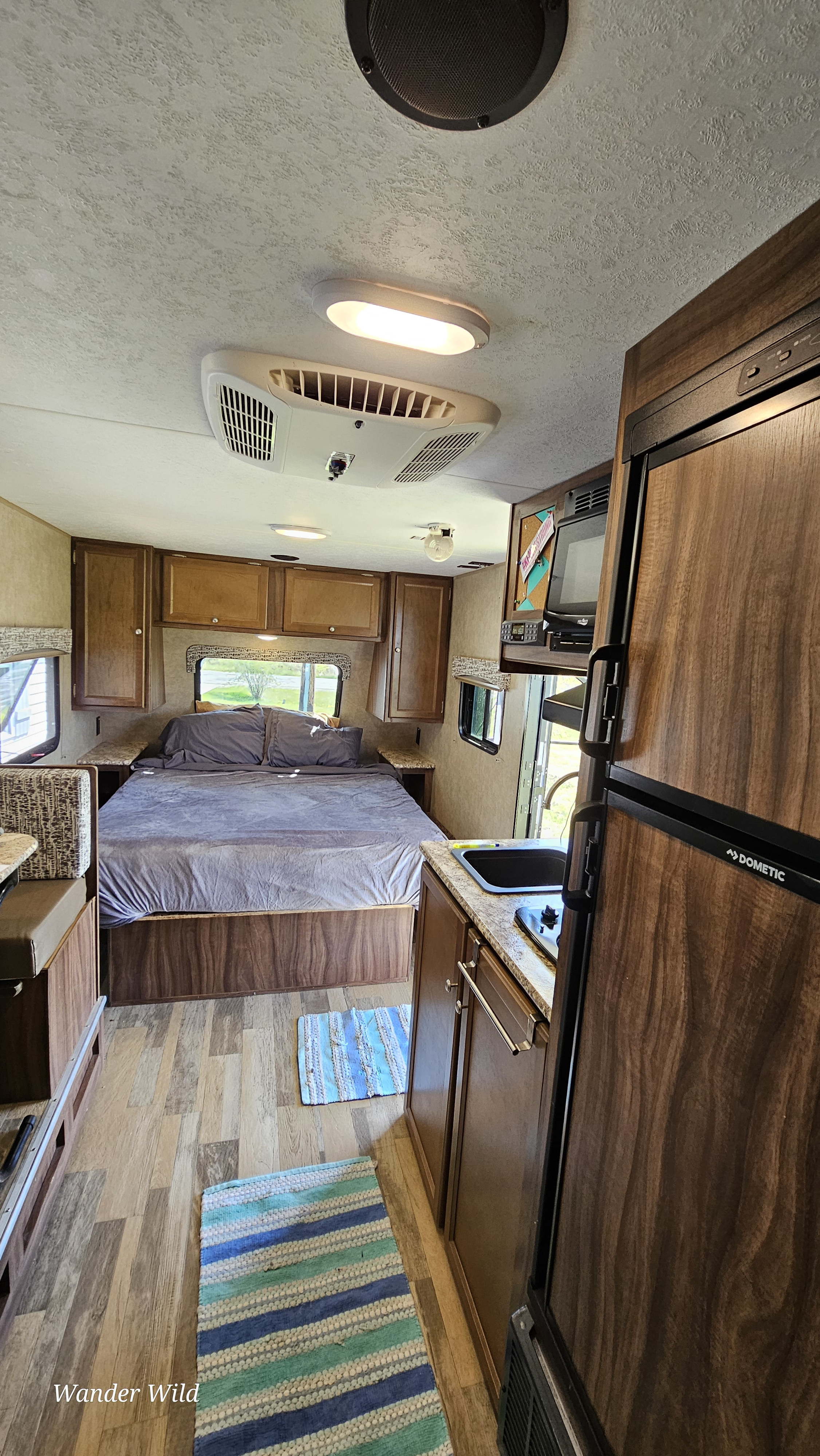 Cozy RV rental interior showing the bed, kitchen, and refrigerator, perfect for compact travel.. Forest River Viking 2018