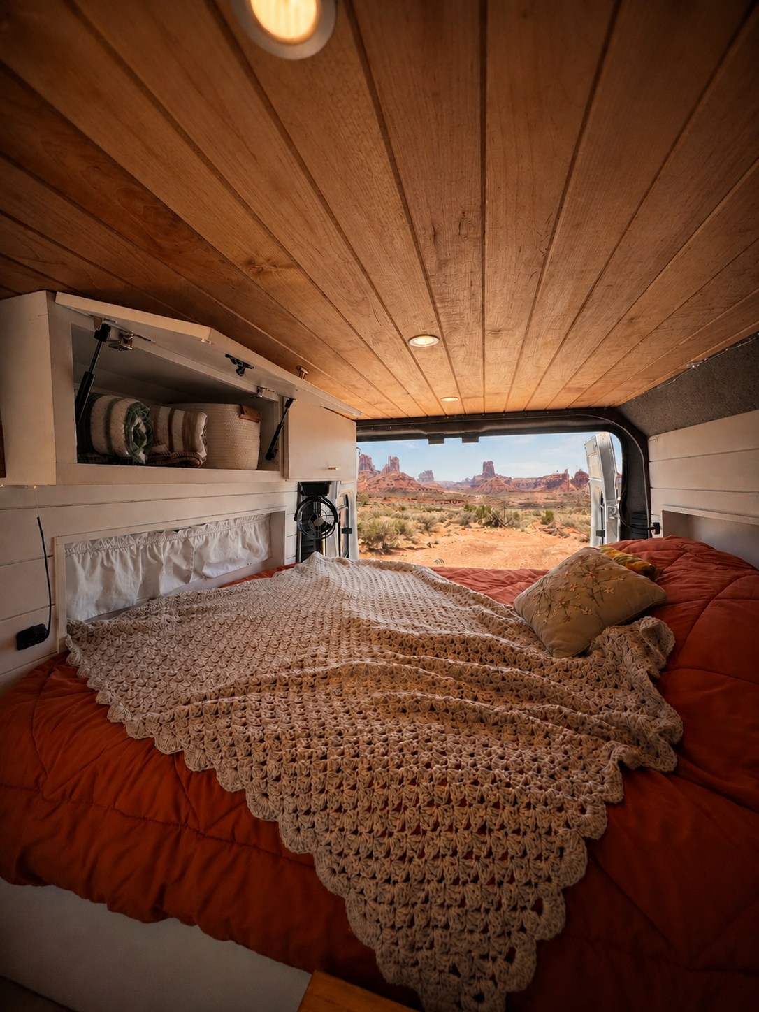 Inside an RV rental: a cozy bed, crochet blanket, wood ceiling, and breathtaking desert views of iconic rock formations.. Dodge Ram Promaster 2020