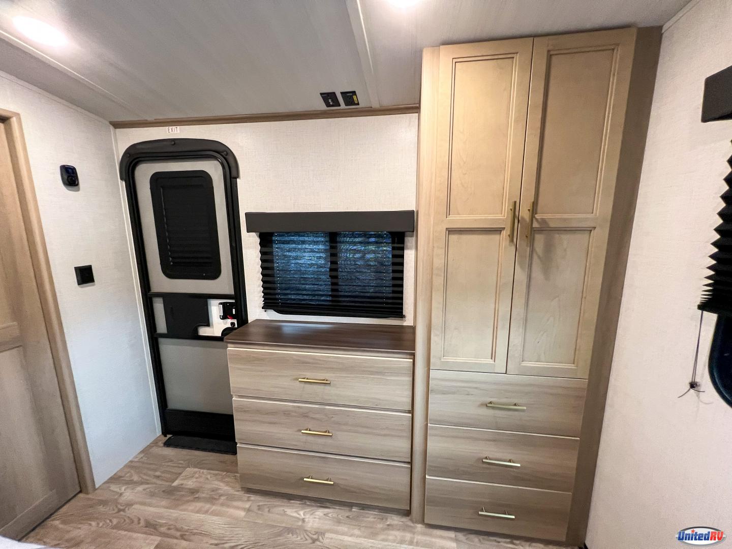 Inside this RV rental, find a light-wood dresser, wardrobe, exit door, and window for your journey.. Keystone RV Outback 2025