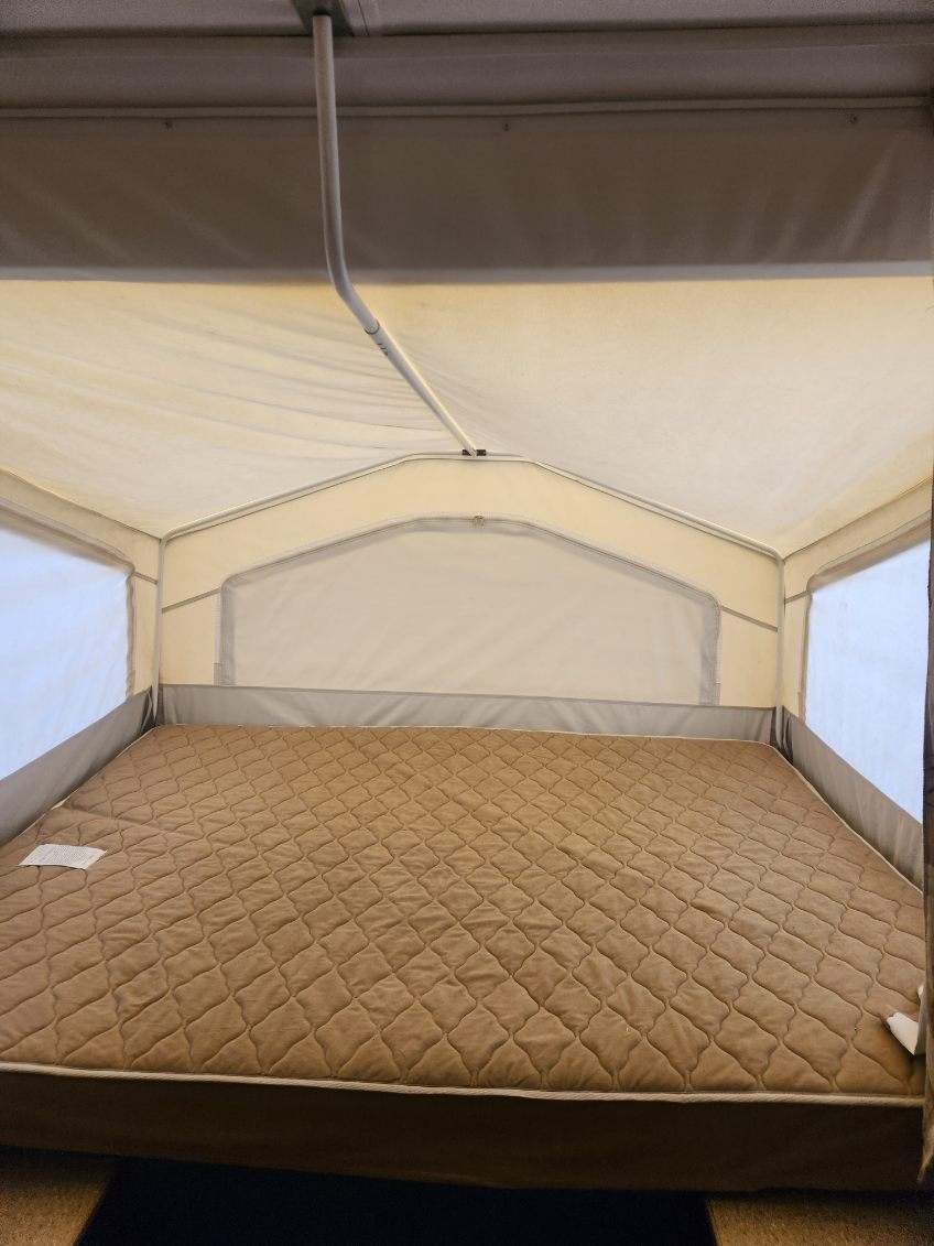 This RV rental offers a comfortable pop-up camper sleeping area with a large, quilted brown mattress.. Forest River Rockwood Freedom 2009