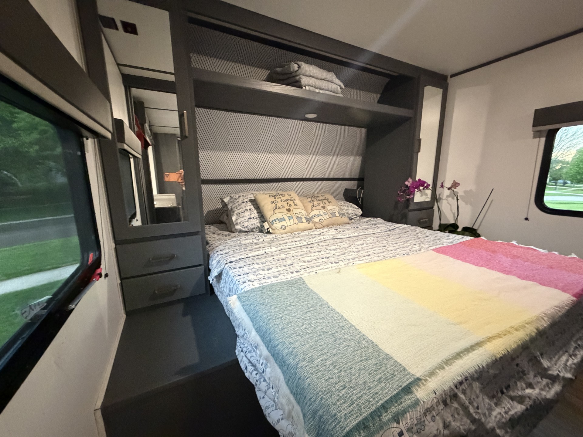 Cozy RV rental bedroom with colorful blanket, camper pillows, and built-in storage. Perfect for travel comfort.. Keystone RV Bullet Crossfire 2022