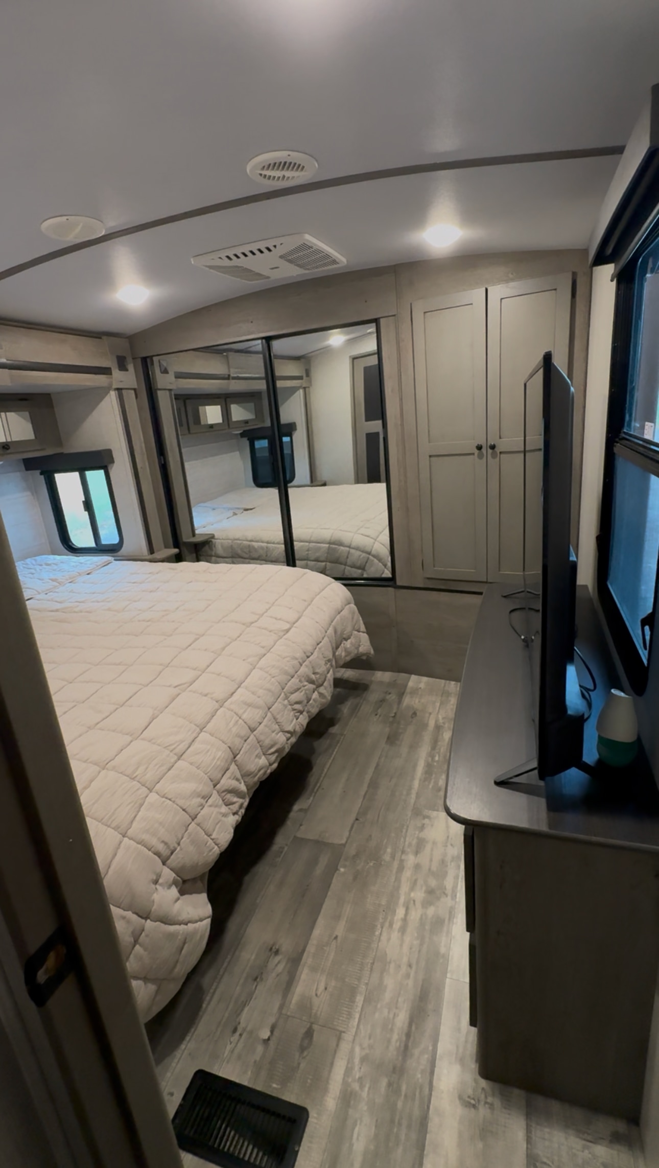 This RV rental bedroom features a comfy bed, mirrored closet, TV, and modern decor, perfect for travelers.. Keystone RV Outback 2021