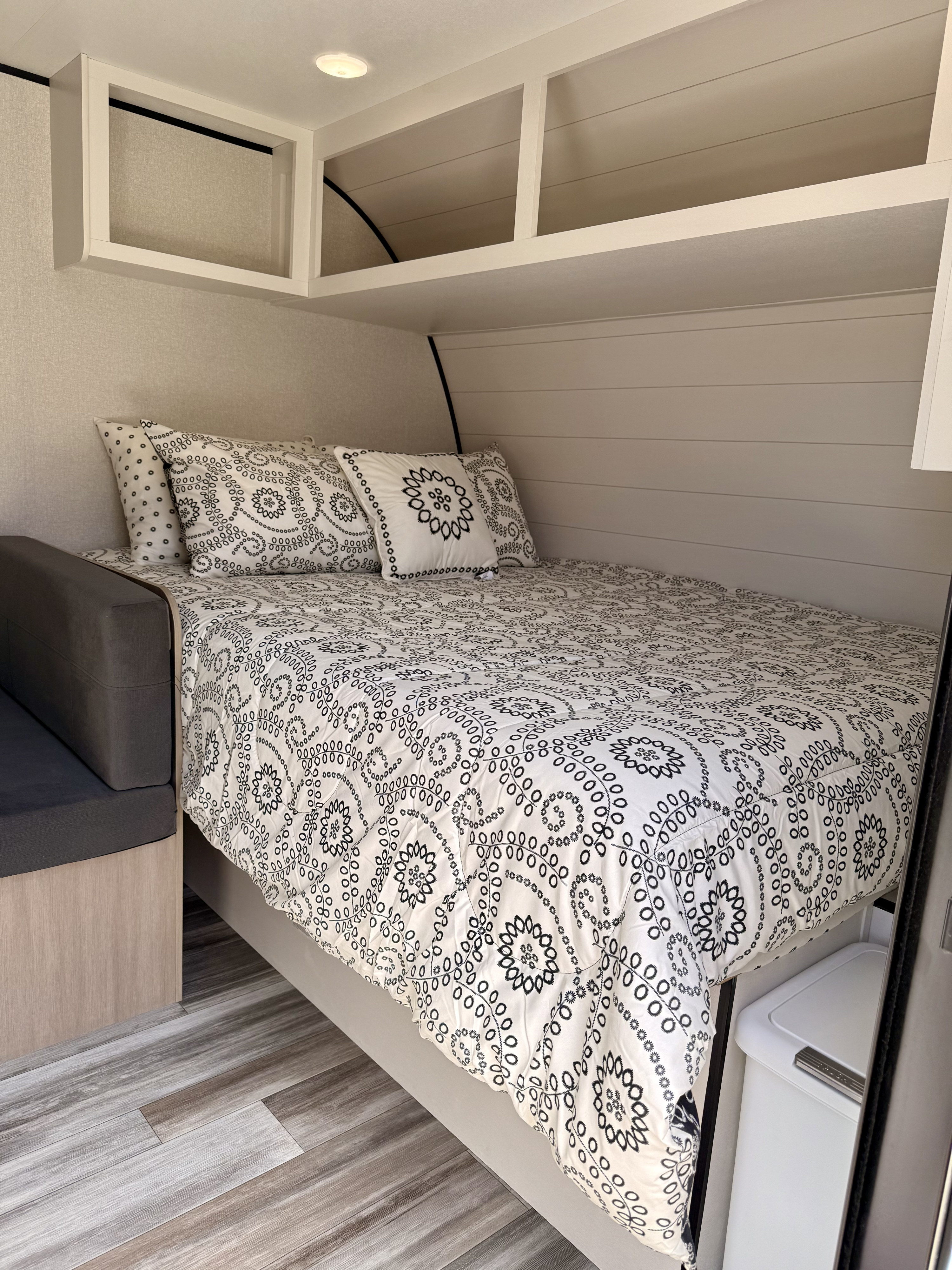 This RV rental offers a compact bedroom with a patterned bed, overhead shelves, and an adjoining upholstered bench.. Jayco 170BH 2026