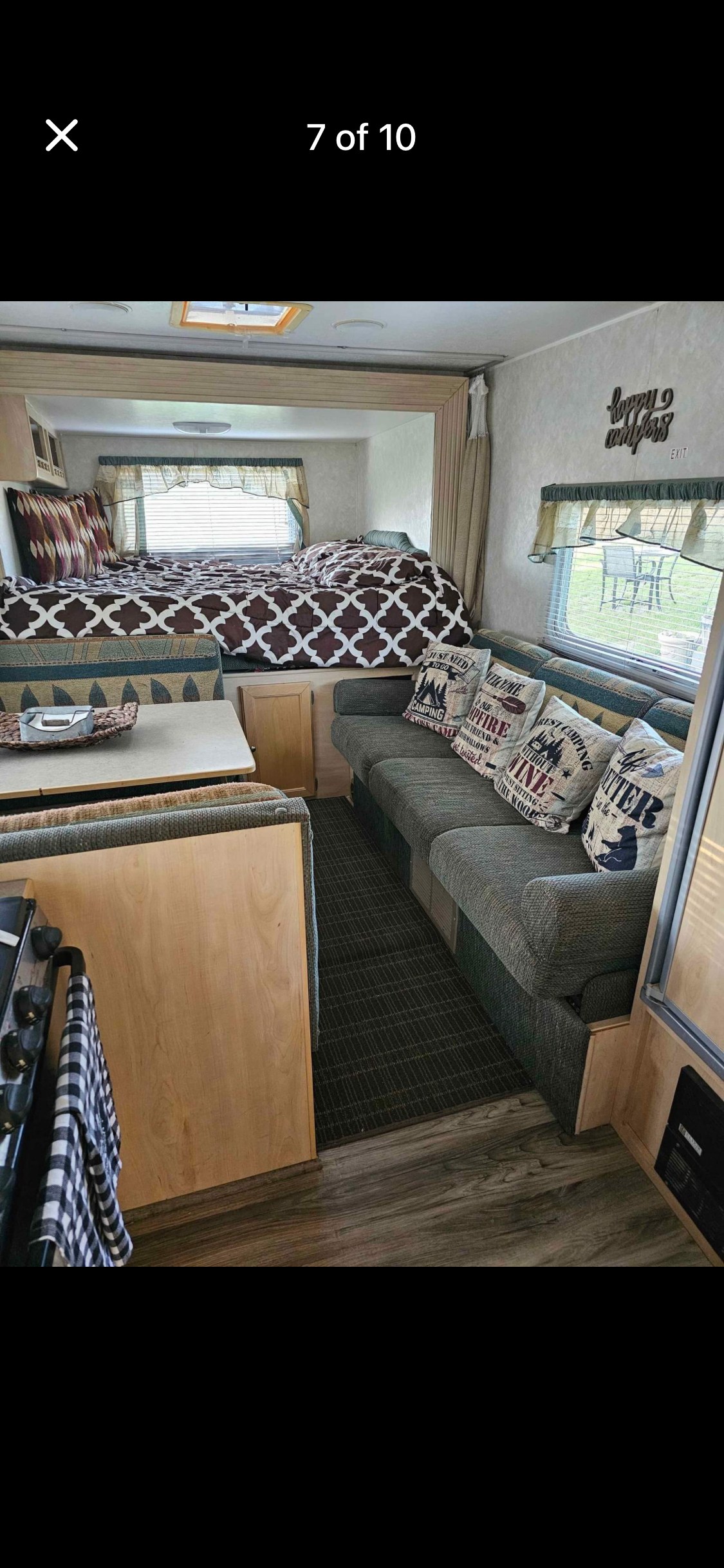 Cozy RV rental interior featuring a comfortable bed, dinette, and sofa with camping pillows. Ready for your next adventure!. Forest River Surveyor Luxury 2004