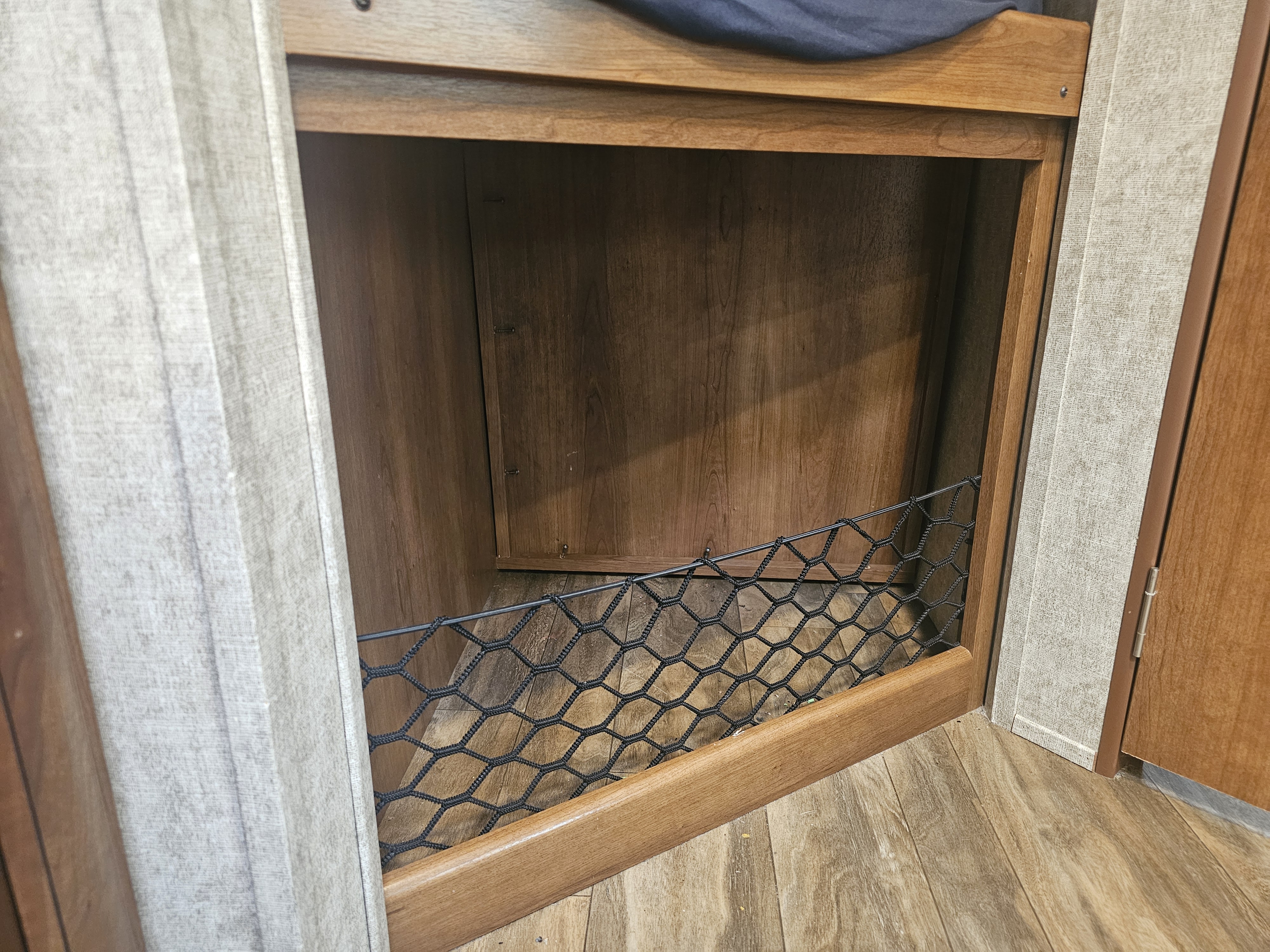 RV rental interior: A wooden storage cubby with a black mesh net front, ideal for holding items in a compact space.. Forest River Tracer Air 2018