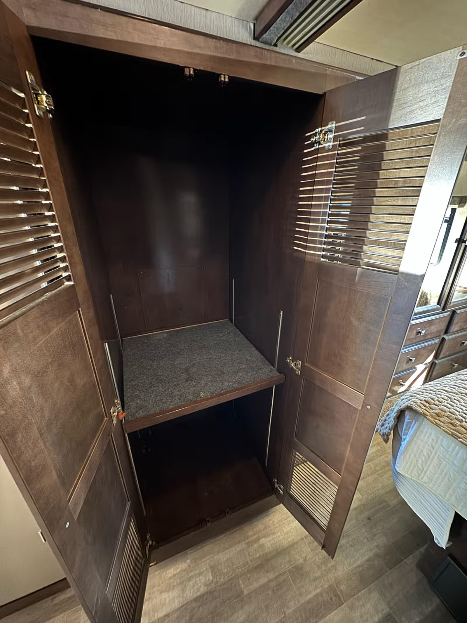 This RV rental features a dark wood wardrobe with a carpeted shelf and hanging rod, offering convenient storage for your belongings.. Holiday Rambler Admiral 2019