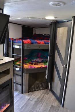 Cozy RV rental interior featuring comfortable bunk beds, a modern design, and a fireplace, ideal for family travel.. Heartland RVs North Trail 2022