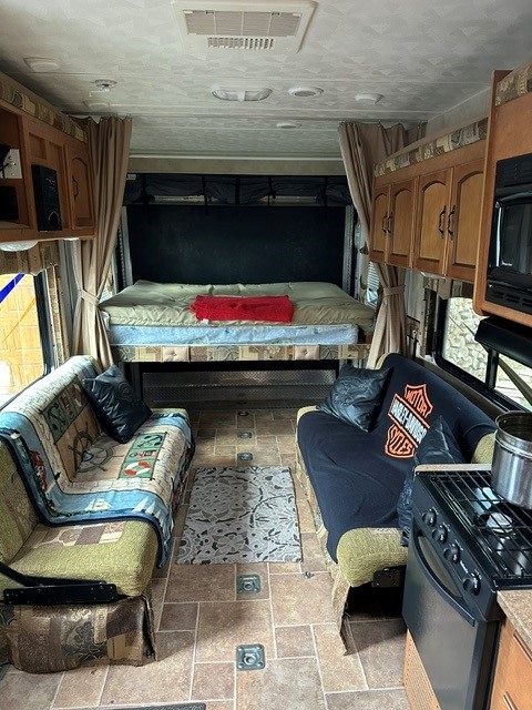 Spacious RV rental interior with a drop-down bed, two sofas, and a compact kitchen. Perfect for adventures on the road.. Forest River Puma 2011