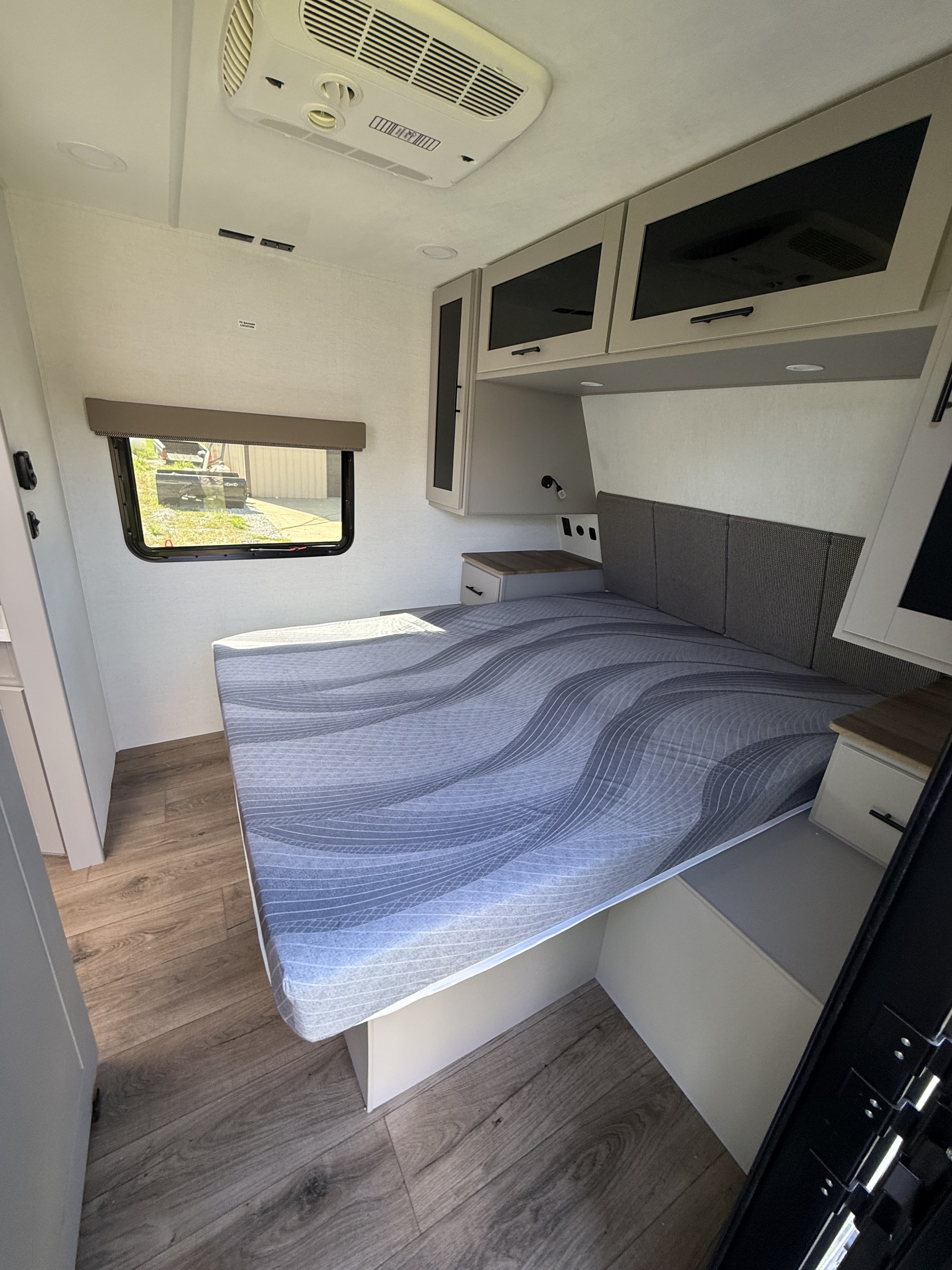 Spacious RV rental bedroom featuring a bed with wavy patterned mattress, overhead storage, window, and AC unit for comfort.. Alliance Delta 291BH 2026