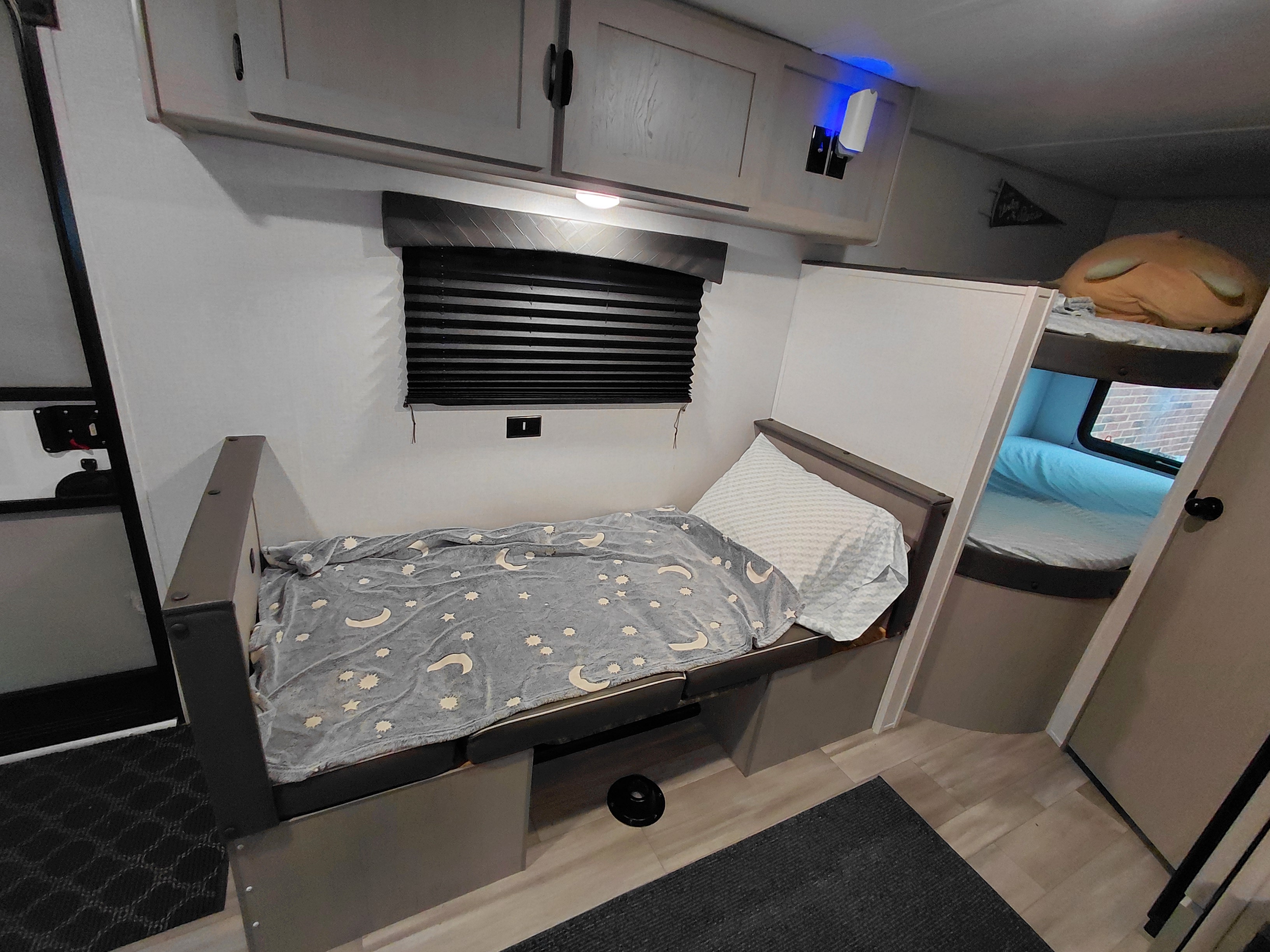 RV rental interior: cozy bed with blanket, bunk beds, and overhead storage cabinets, ideal for a comfortable stay.. Forest River Coachmen Clipper Sport 2024