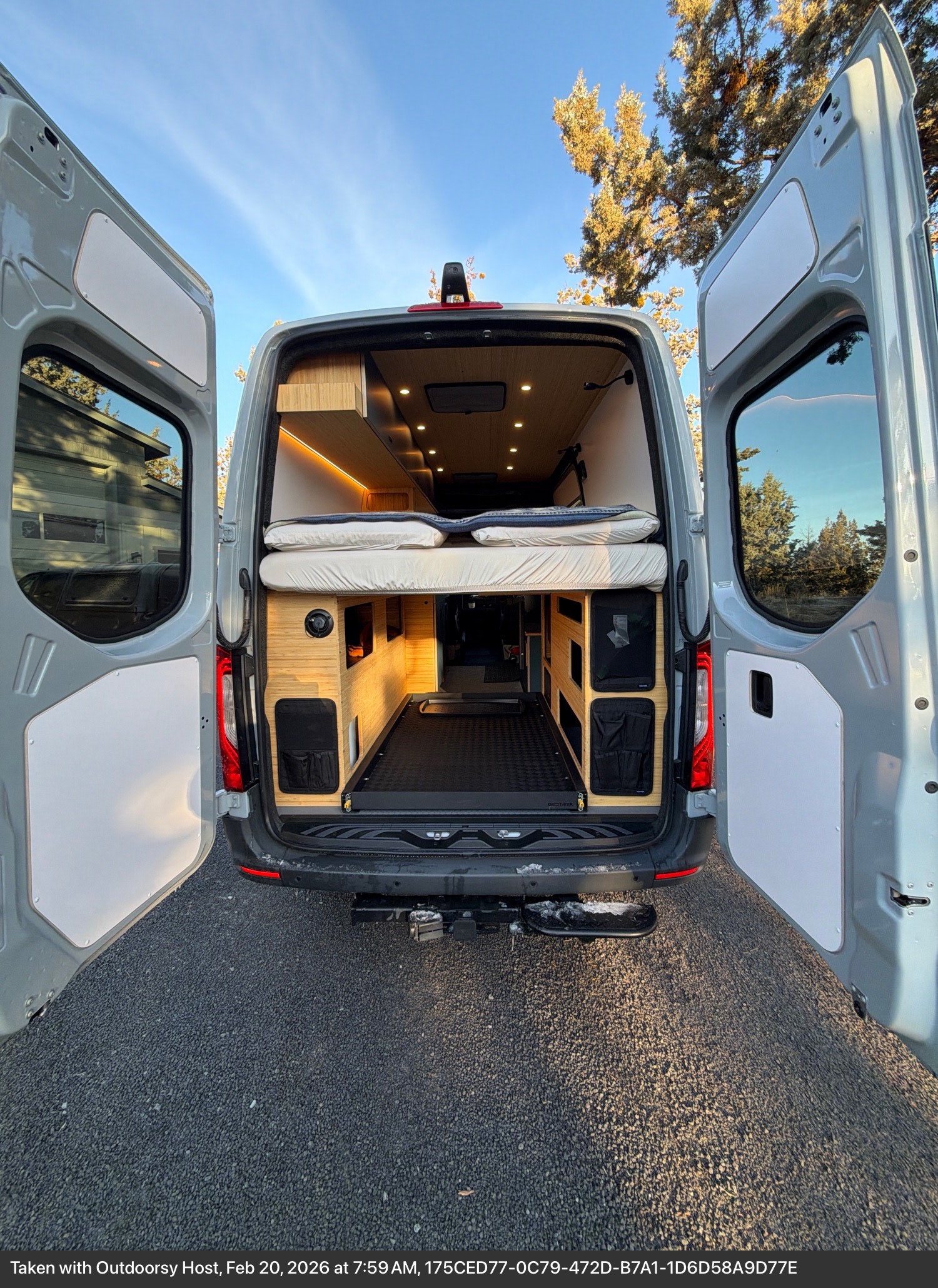 Explore this camper van rv rental's spacious interior: open rear doors reveal a raised bed, ample storage, and cargo slide.. W1Y4NBVY4ST232112 Geotrek 2025