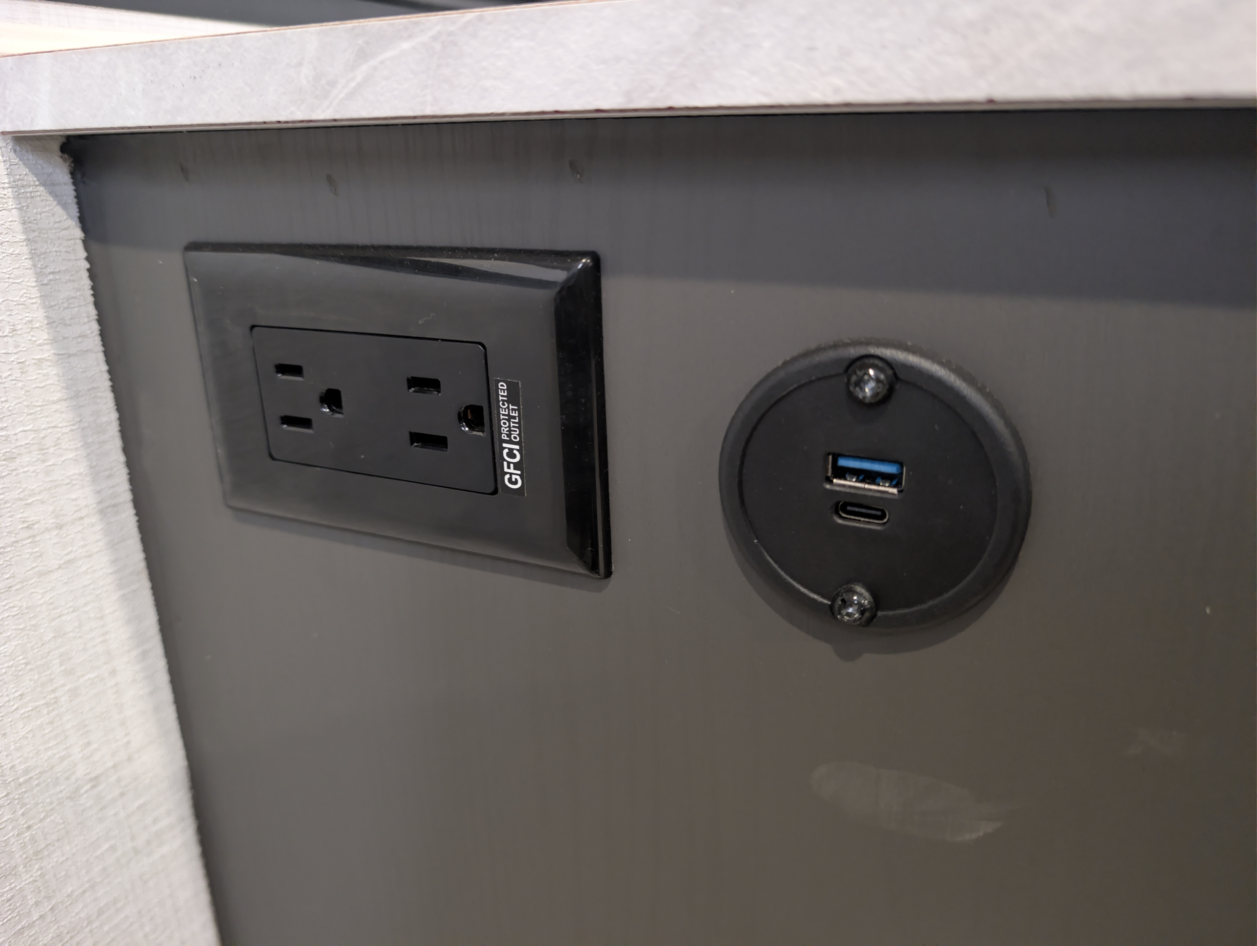 RV rental power hub: GFCI electrical outlet & USB-A/C charging ports on a dark panel for your devices.. Forest River Rockwood Freedom 2025