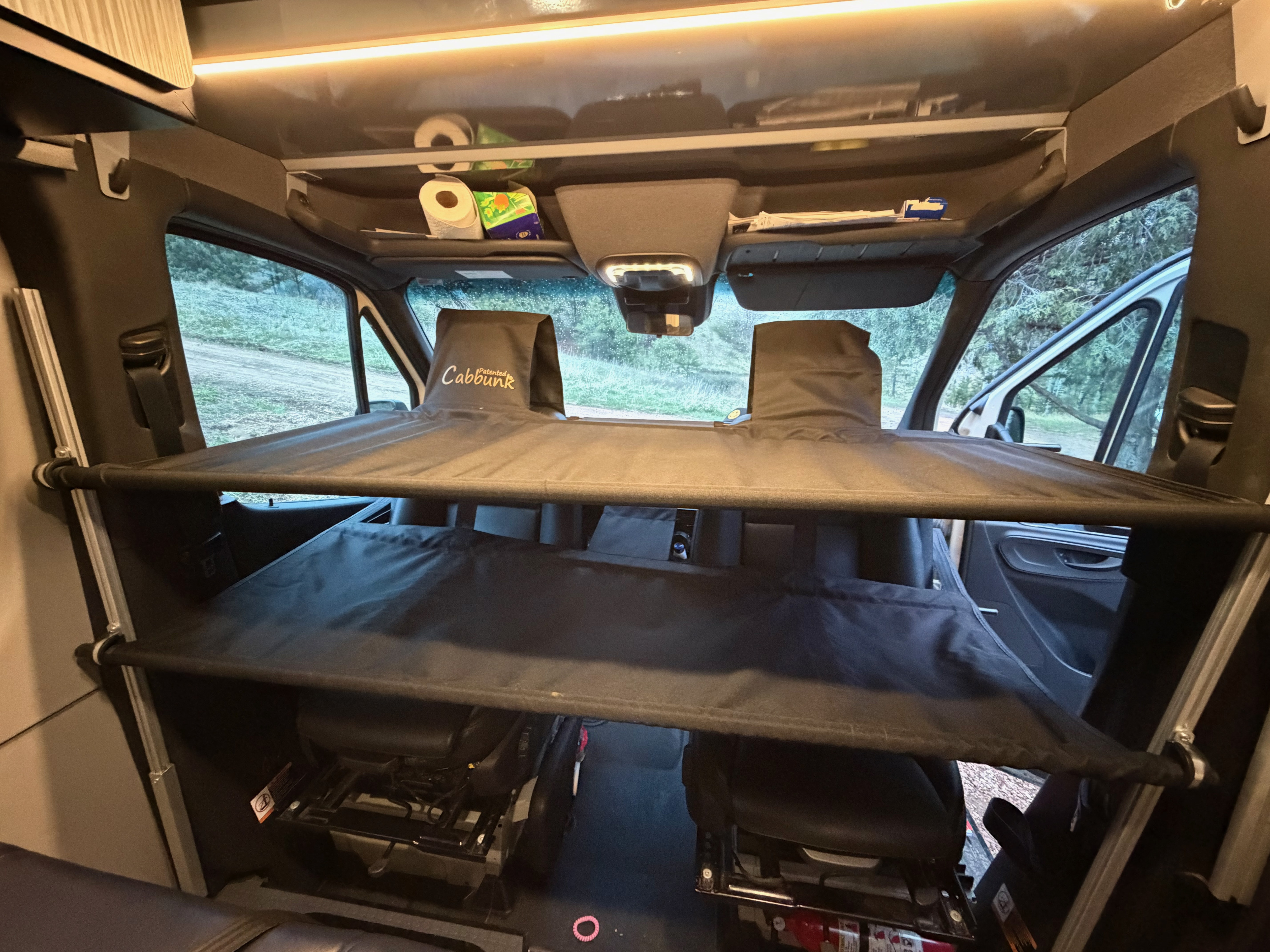 Cab area of an RV rental featuring a "Cabbunk" bunk bed system over the front seats and overhead storage.. Winnebago Revel 2022