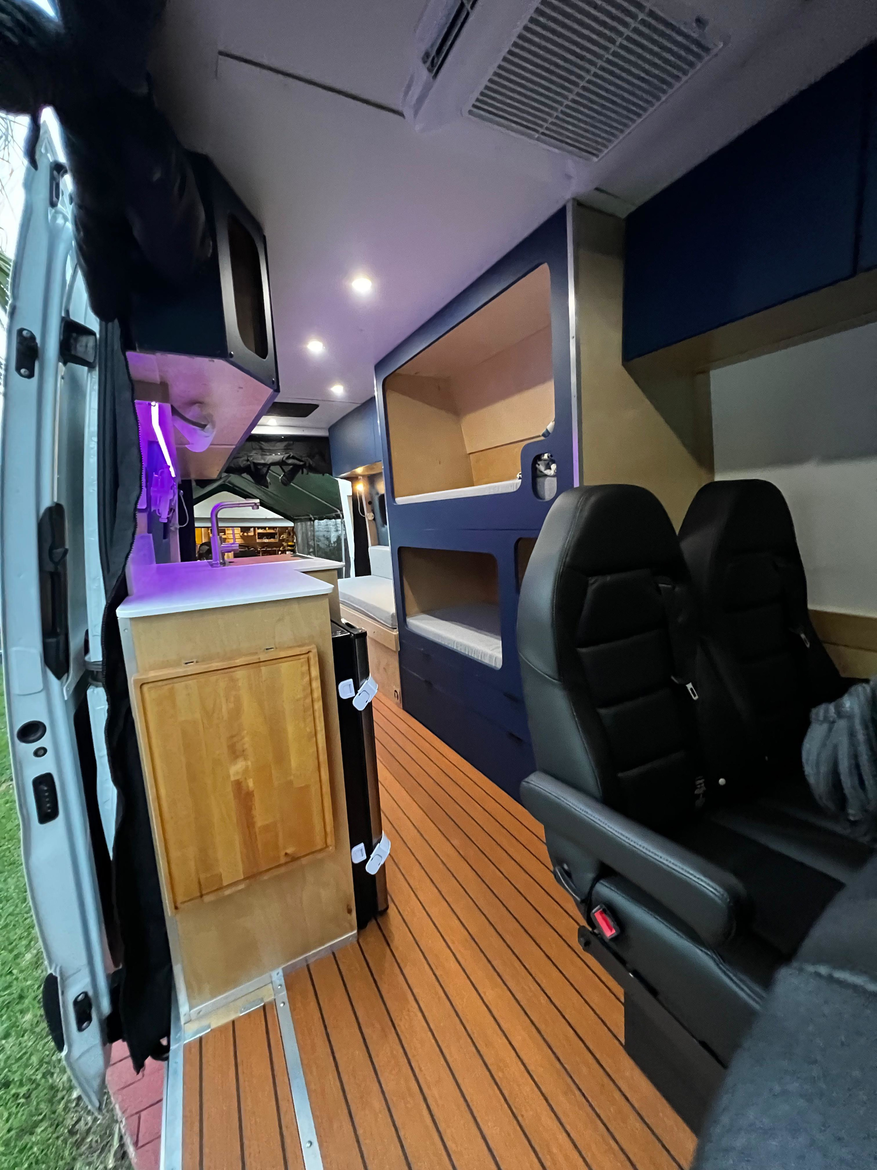 Explore this comfy RV rental interior: bunk beds, modern kitchen with purple LEDs, and plush seating for your adventures.. Mercedes-Benz Sprinter 2023