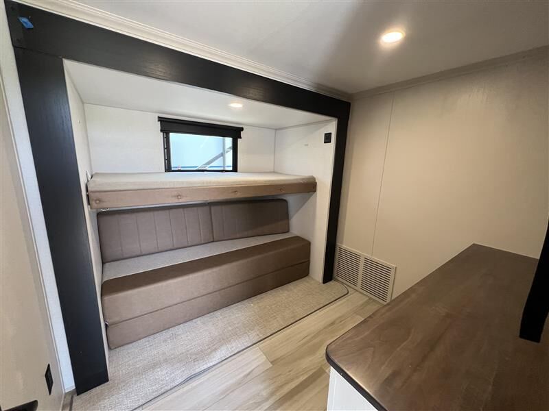 This RV rental bunkhouse offers a cozy interior with a top bunk, convertible sofa bed below, window, and wood-look flooring.. Forest River Salem Hemisphere 2025