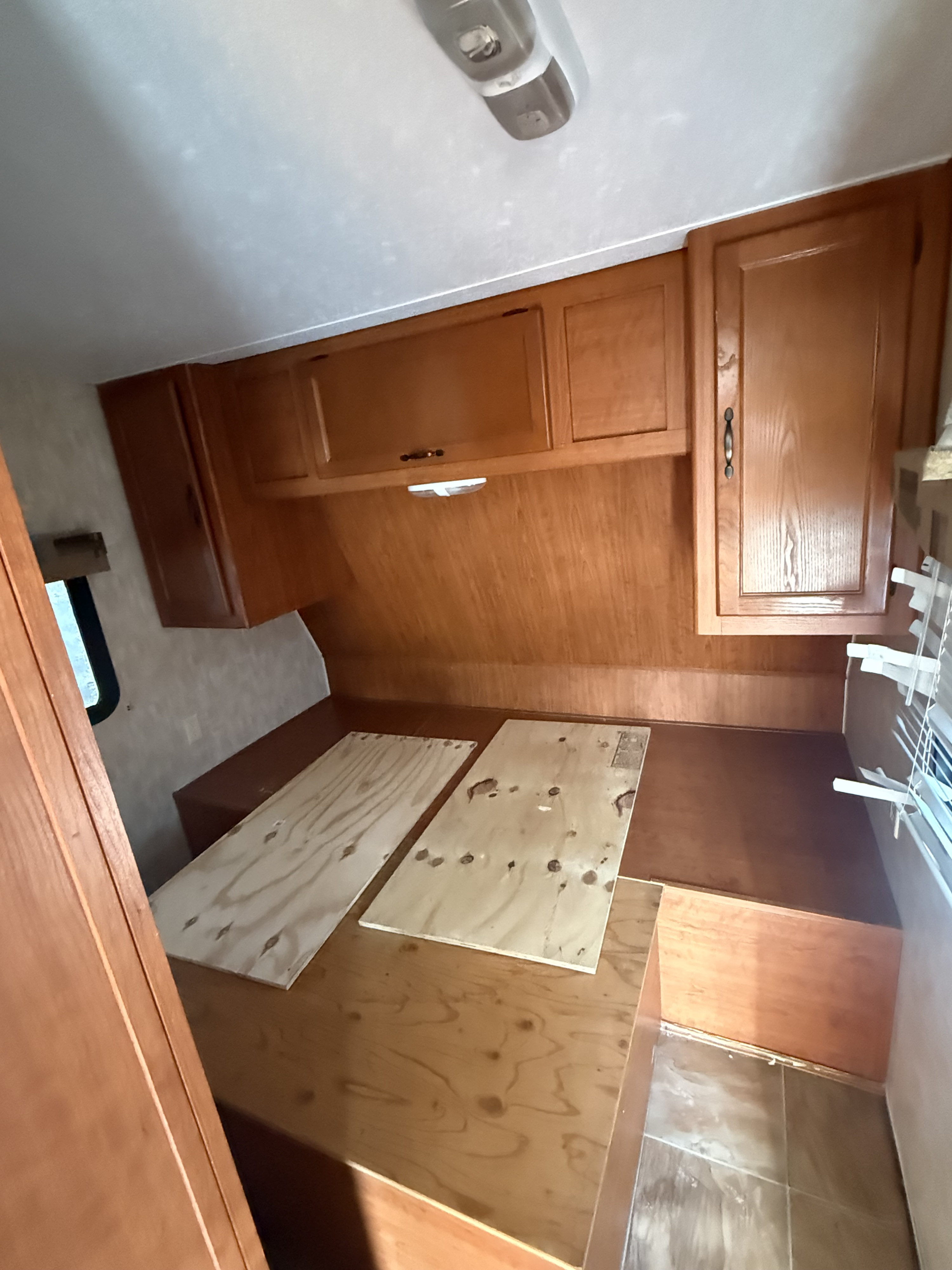 RV rental interior: wooden cabinets, light fixture, and a convertible bed/seating area with plywood base.. Forest River Cherokee Grey Wolf 2010