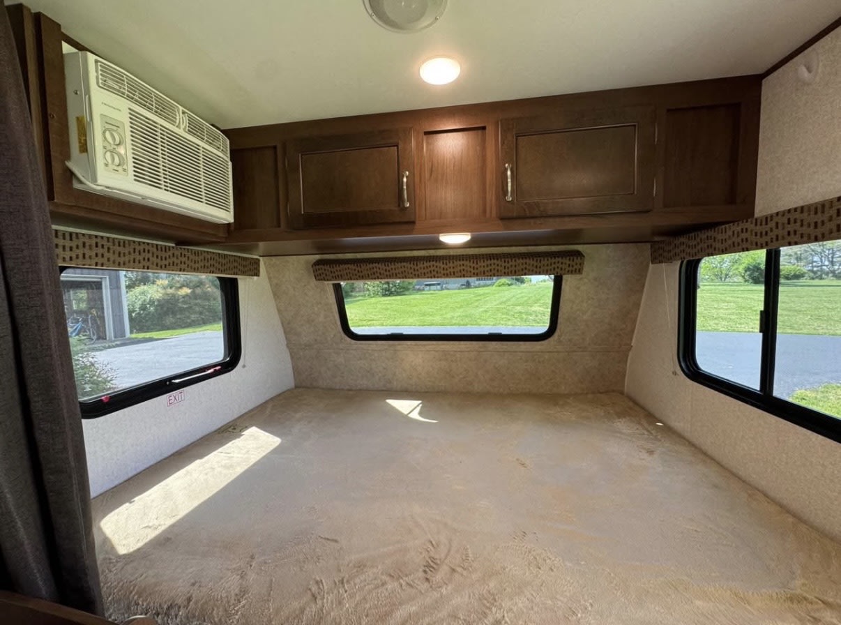 RV rental: Bright bedroom with a large platform bed, windows revealing outdoor scenery, an AC unit, and overhead cabinets.. Jayco Jay Flight SLX 2017