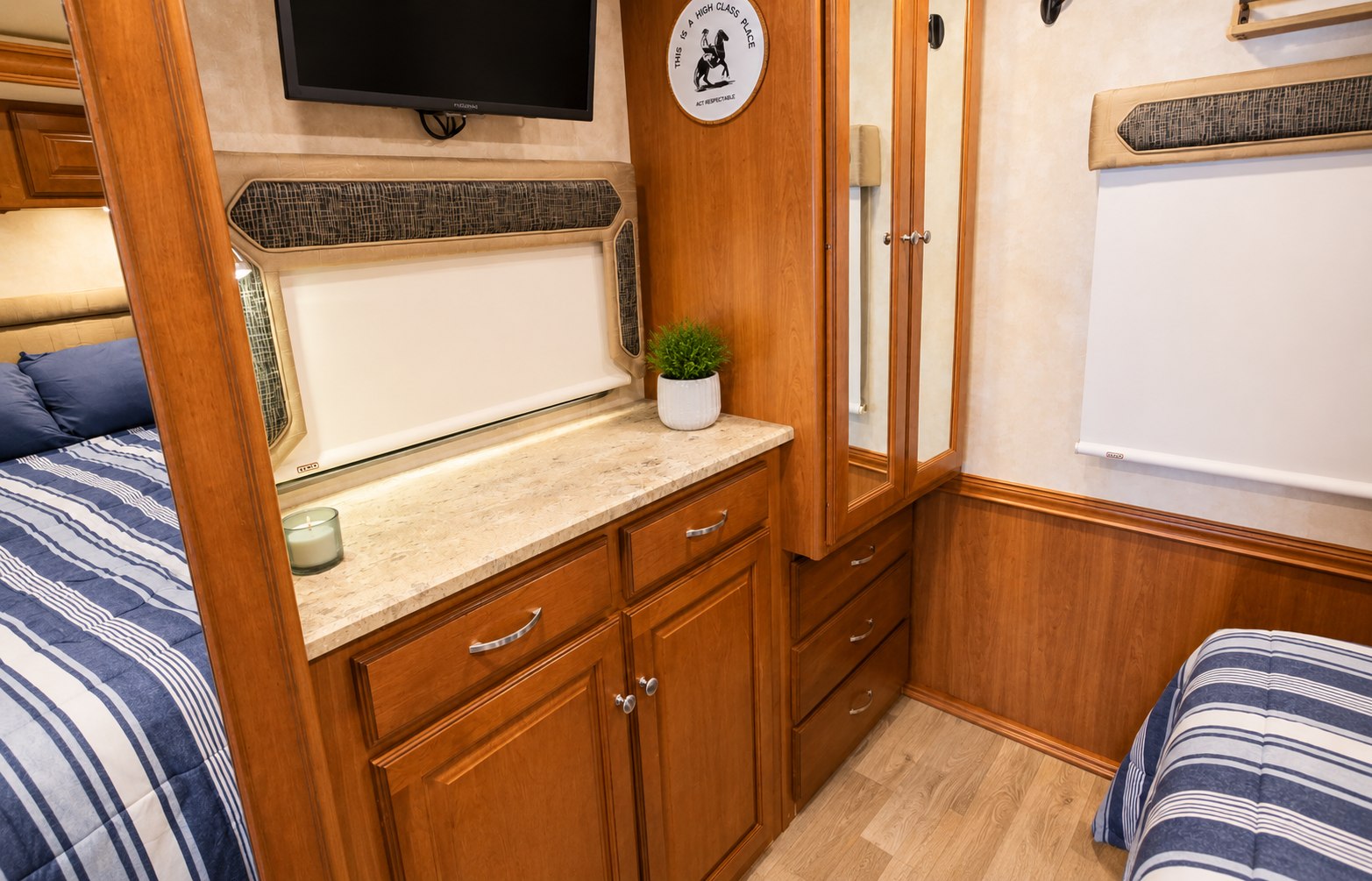Explore this well-appointed RV rental bedroom, featuring a comfortable bed, built-in storage, TV, and decorative elements.. Winnebago Vista LX 2019