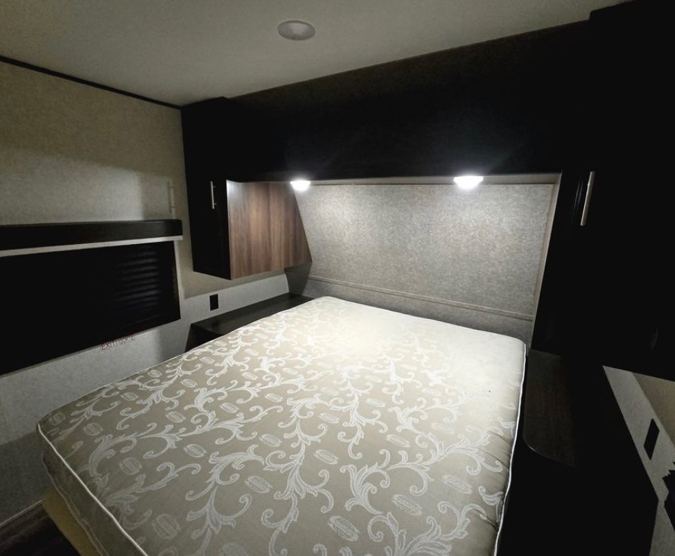 Cozy RV rental bedroom interior with a comfortable bed, overhead storage, and window. Your perfect camper retreat.. Jayco Jay Flight 2019