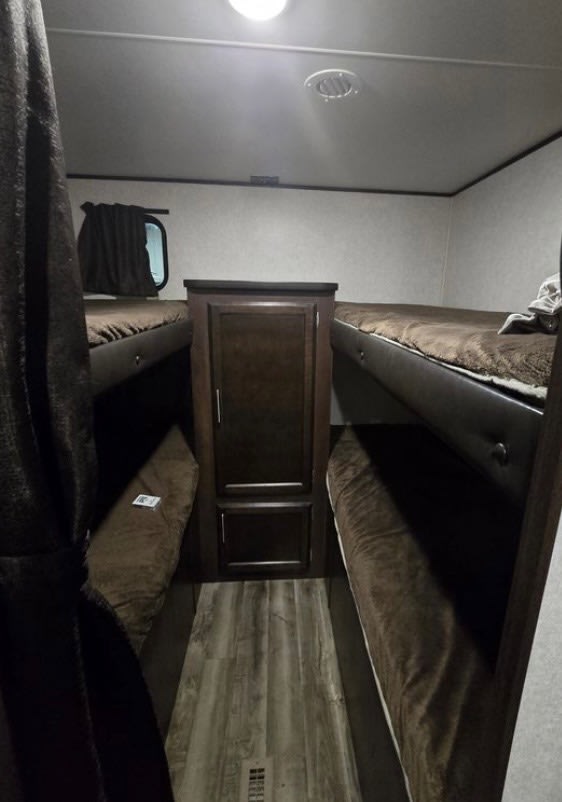 Cozy RV rental bunk beds flank a central cabinet, offering compact sleeping space within this camper's efficient interior.. Jayco Jay Flight 2019