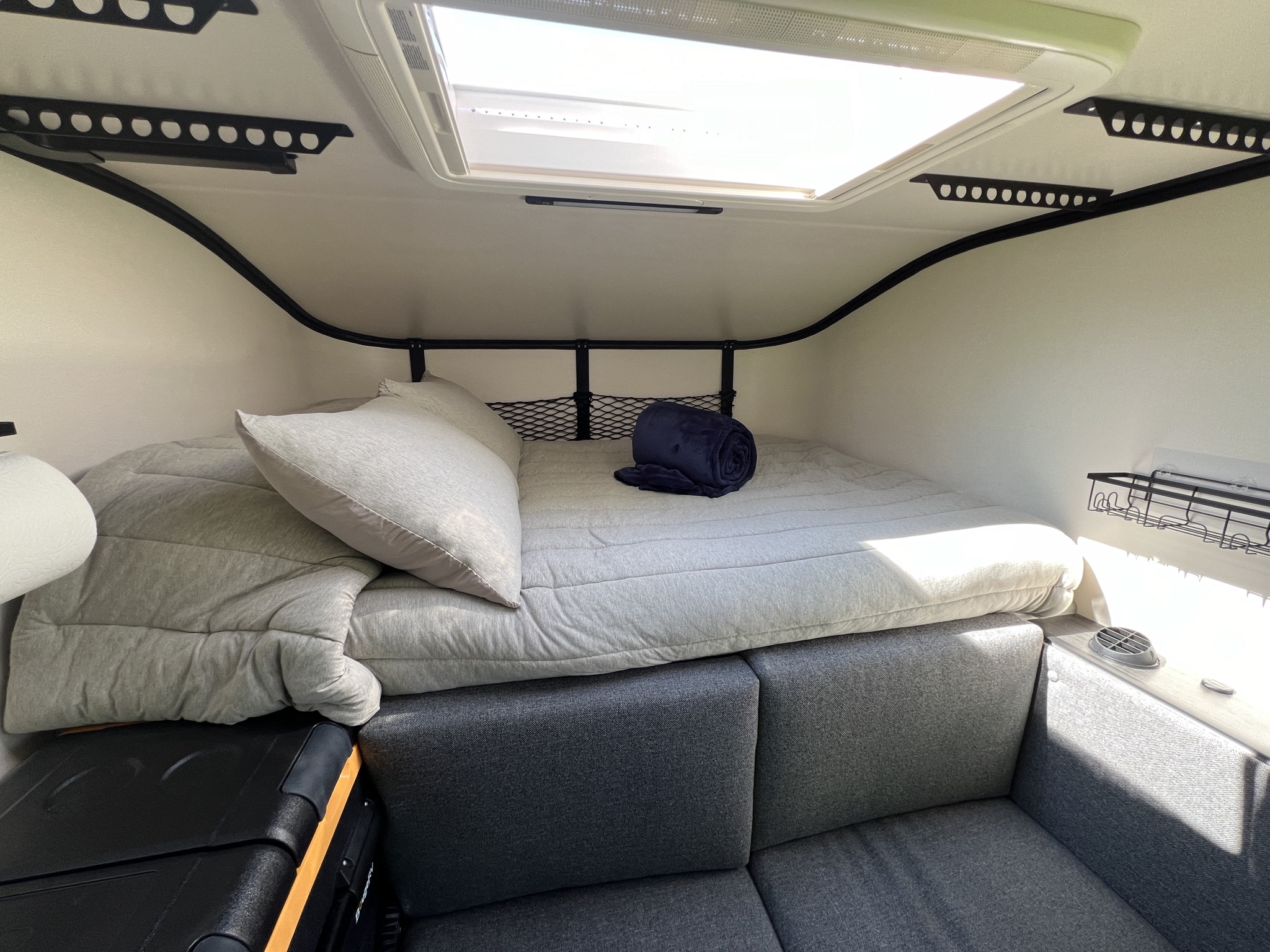 Inside a modern rv rental: a comfy bed, seating area, skylight, and storage. Ideal for road trip adventures.. Toyota Tacoma 2026
