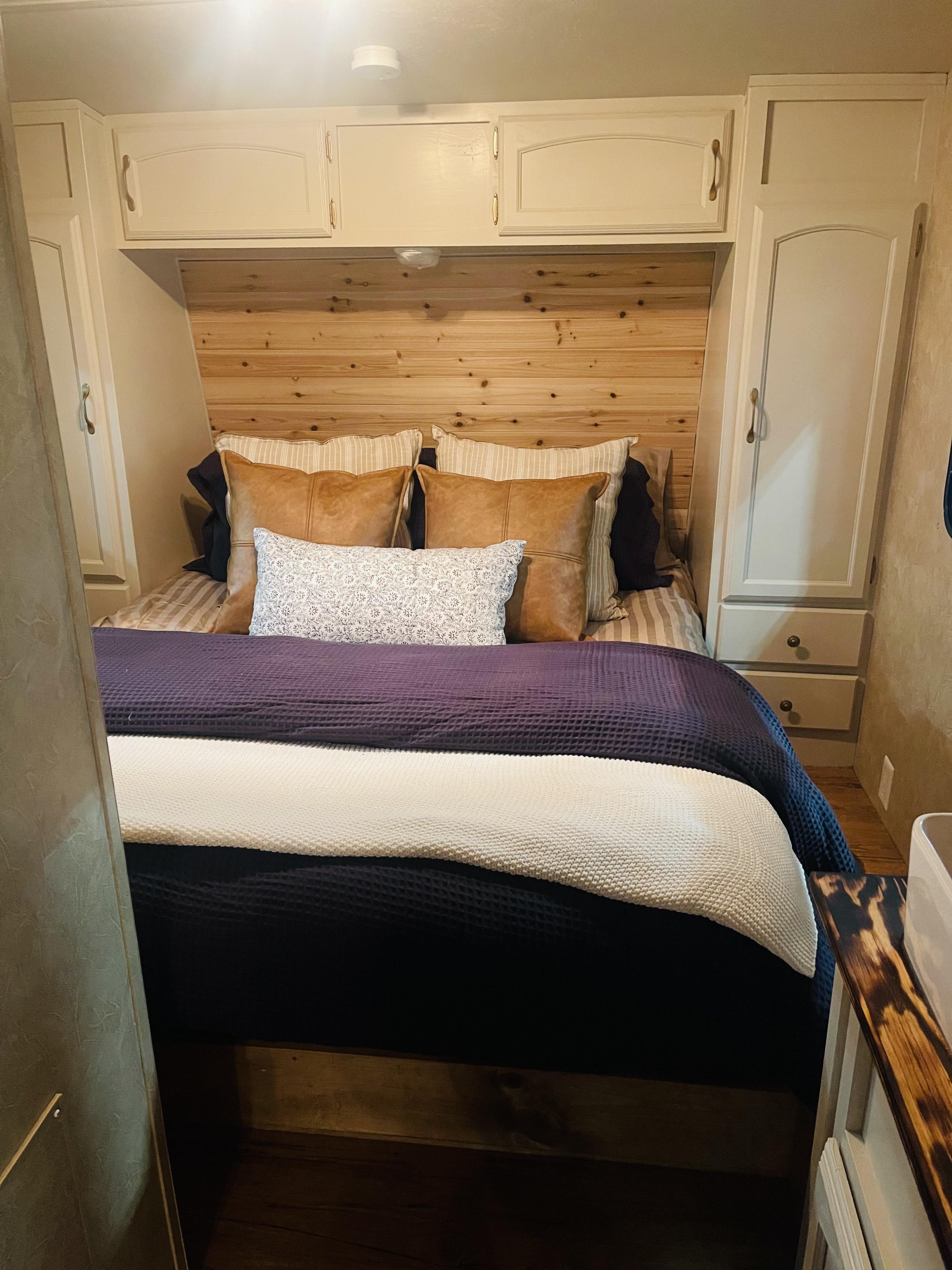 A comfortable RV rental bedroom featuring a paneled wood headboard, built-in cabinets, and layered blankets.. Forest River Salem LE 2010