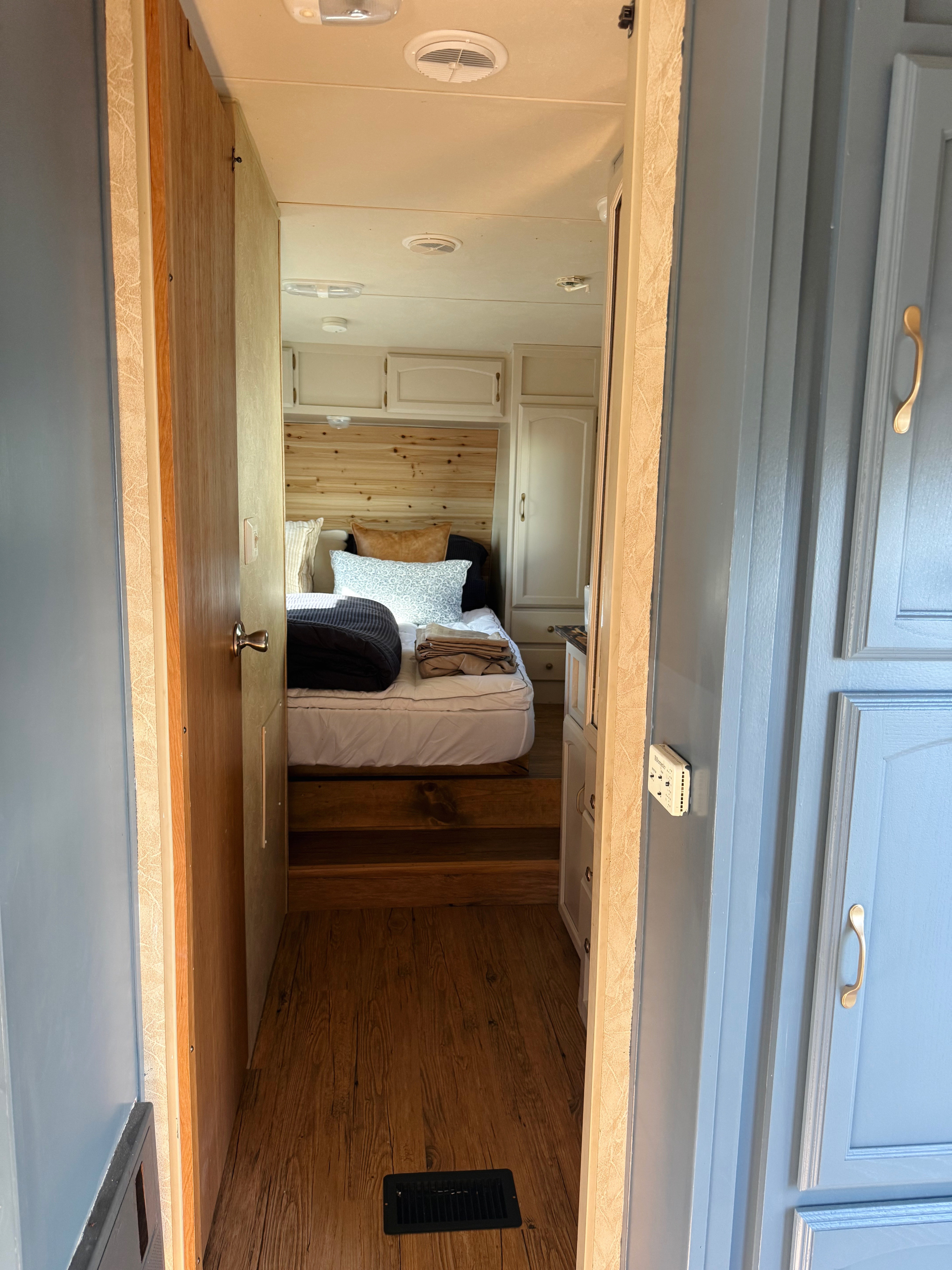 RV rental: Interior hallway looking into a bedroom with a bed, wooden headboard, light cabinetry, and wood laminate flooring.. Forest River Salem LE 2010